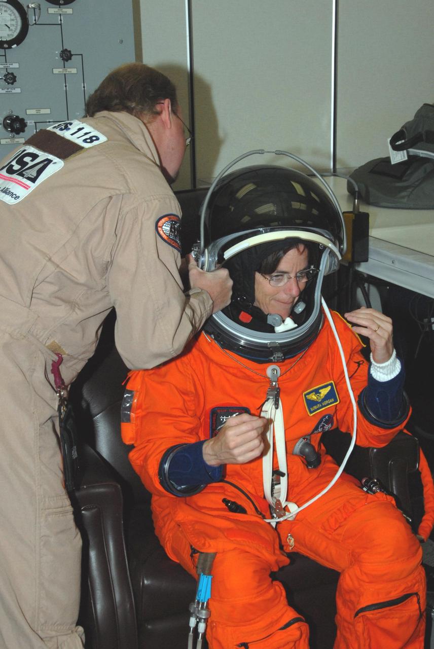 KENNEDY SPACE CENTER, Fla.  --  STS-118 Mission Specialist Barbara R. Morgan is helped with her helmet during suitup for the simulated launch countdown that concludes the terminal countdown demonstration test, or TCDT. Teacher-turn-astronaut Morgan is making her first space flight. The STS-118 crew has been at Kennedy for the TCDT activities that also include M-113 training, payload familiarization and emergency egress training at the pad.  The mission is the 22nd flight to the International Space Station and Space Shuttle Endeavour will carry a payload including the S5 truss, a SPACEHAB module and external stowage platform 3. STS-118 is targeted for launch on Aug. 7.  Photo credit: NASA/George Shelton
