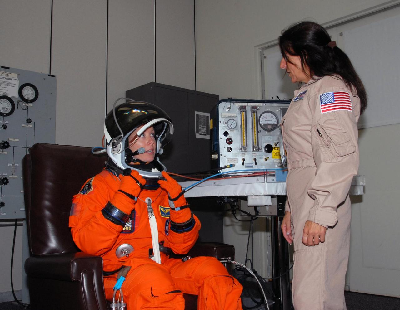 KENNEDY SPACE CENTER, Fla.  --  STS-118 Mission Specialist Tracy Caldwell fixes her helmet during suitup for the simulated launch countdown that concludes the terminal countdown demonstration test, or TCDT. The STS-118 crew has been at Kennedy for the TCDT activities that also include M-113 training, payload familiarization and emergency egress training at the pad.  The mission is the 22nd flight to the International Space Station and Space Shuttle Endeavour will carry a payload including the S5 truss, a SPACEHAB module and external stowage platform 3. STS-118 is targeted for launch on Aug. 7.  Photo credit: NASA/George Shelton