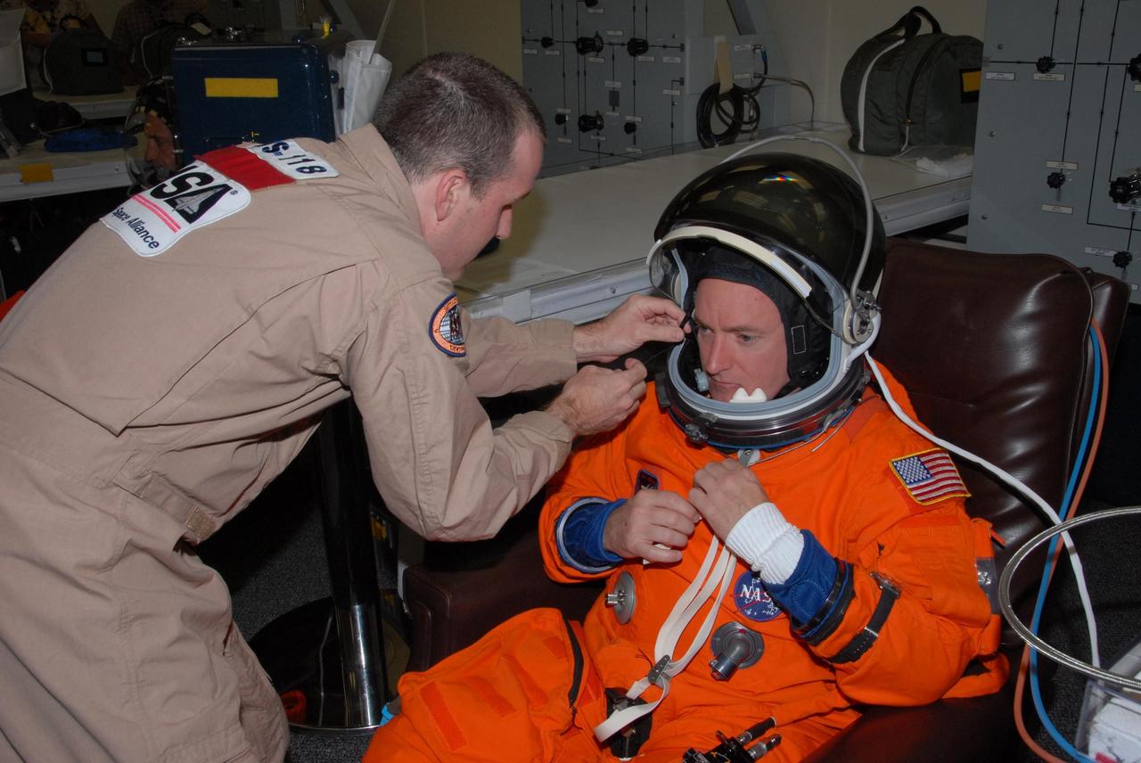 KENNEDY SPACE CENTER, Fla. -- STS-118 Commander Scott Kelly gets help suiting up before the simulated launch countdown that concludes the terminal countdown demonstration test, or TCDT. The STS-118 crew has been at Kennedy for the TCDT activities that also include M-113 training, payload familiarization and emergency egress training at the pad. The mission is the 22nd flight to the International Space Station and Space Shuttle Endeavour will carry a payload including the S5 truss, a SPACEHAB module and external stowage platform 3. STS-118 is targeted for launch on Aug. 7. Photo credit: NASA/George Shelton