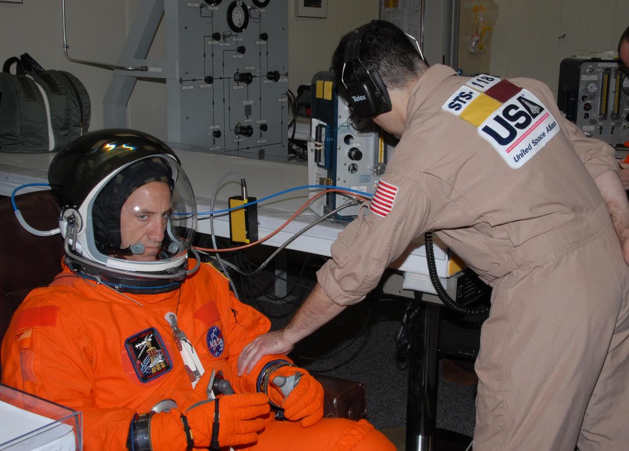 KENNEDY SPACE CENTER, Fla.  --    STS-118 Pilot Charlie Hobaugh's launch and entry suit is monitored after his suitup for the simulated launch countdown that concludes the terminal countdown demonstration test, or TCDT. The STS-118 crew has been at Kennedy for the TCDT activities that also include M-113 training, payload familiarization and emergency egress training at the pad.  The mission is the 22nd flight to the International Space Station and Space Shuttle Endeavour will carry a payload including the S5 truss, a SPACEHAB module and external stowage platform 3. STS-118 is targeted for launch on Aug. 7.  Photo credit: NASA/George Shelton