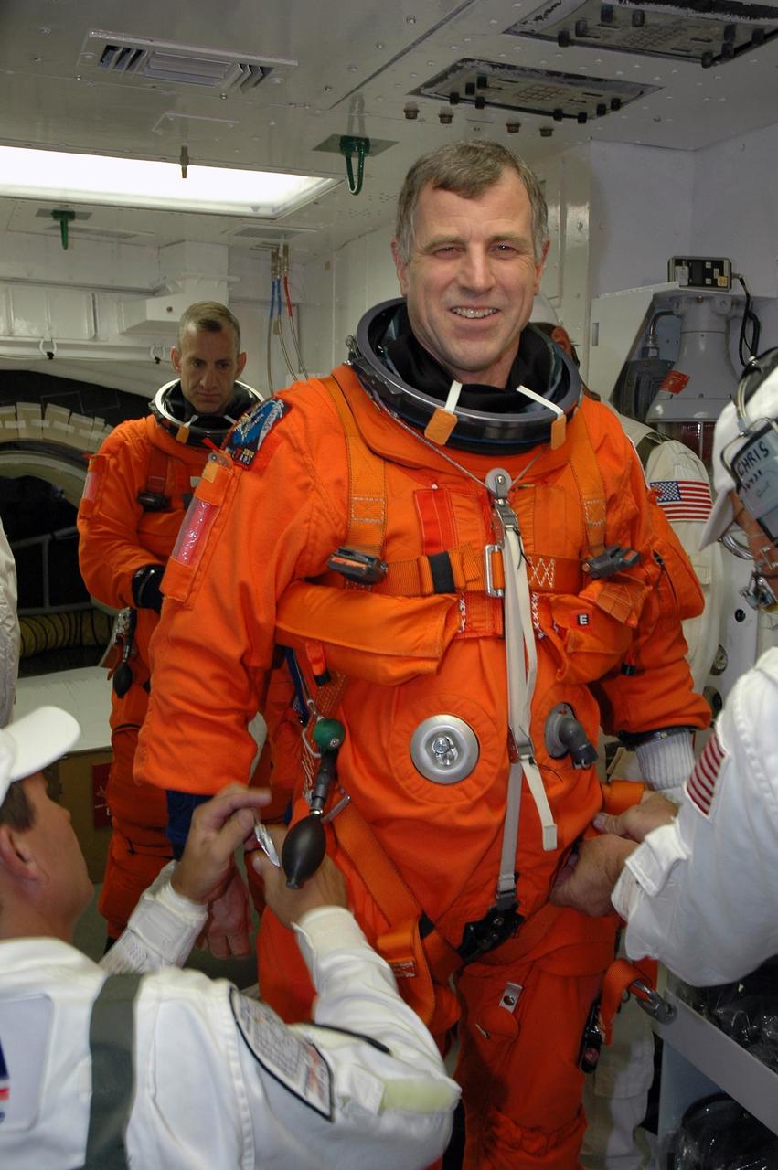 KENNEDY SPACE CENTER, Fla.  -- In the White Room on Launch Pad 39A, STS-118 Mission Specialist Dave Williams waits for the closeout crew to finish checking his launch and entry suit before he enters Space Shuttle Endeavour.  Behind Williams is Pilot Charlie Hobaugh.  Williams, who represents the Canadian Space Agency, and the rest of the crew are taking part in a simulated launch countdown, the culmination of terminal countdown demonstration test activities.  The White Room is situated at the end of the orbiter access arm and provides entry into the orbiter. TCDT activities also include M-113 training, payload familiarization and emergency egress training at the pad.  The mission is the 22nd flight to the International Space Station and Space Shuttle Endeavour will carry a payload including the S5 truss, a SPACEHAB module and external stowage platform 3. STS-118 is targeted for launch on Aug. 7.  Photo credit: NASA/Amanda Diller
