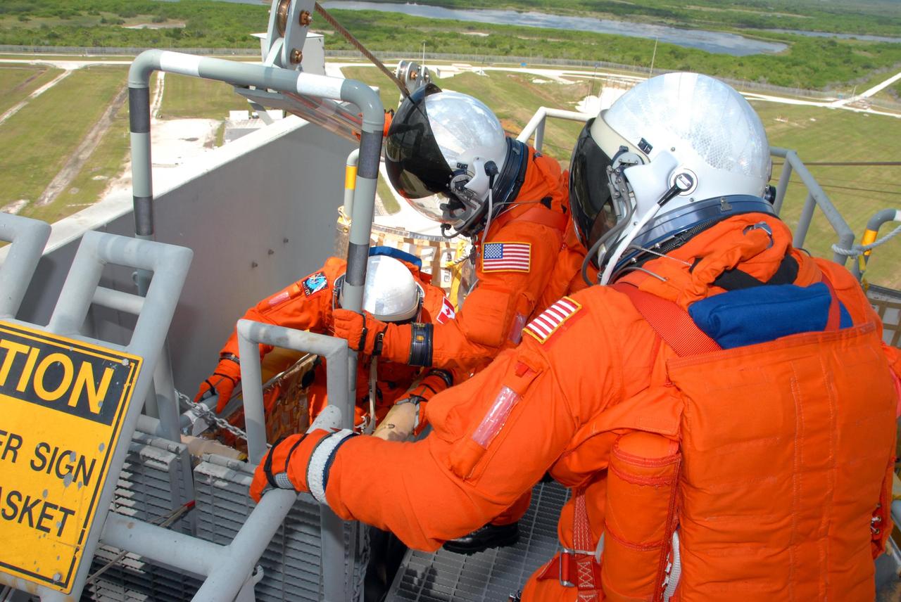 KENNEDY SPACE CENTER, Fla.  --  Practicing emergency egress from Launch Pad 39A, STS-118 crew members climb into a slidewire basket.  They are taking part in terminal countdown demonstration test activities that included a simulated launch countdown.  The crew comprises Commander Scott Kelly, Pilot Charlie Hobaugh and Mission Specialists Dave Williams, Barbara R. Morgan, Rick Mastracchio, Tracy Caldwell and Alvin Drew.  Williams represents the Canadian Space Agency.  Morgan joined NASA's Teacher in Space program in 1985 and was selected as an astronaut in 1998.  The STS-118 mission on Space Shuttle Endeavour is the 22nd flight to the International Space Station and will carry a payload including the S5 truss, a SPACEHAB module and external stowage platform 3. STS-118 is targeted for launch on Aug. 7.  Photo credit: NASA/George Shelton