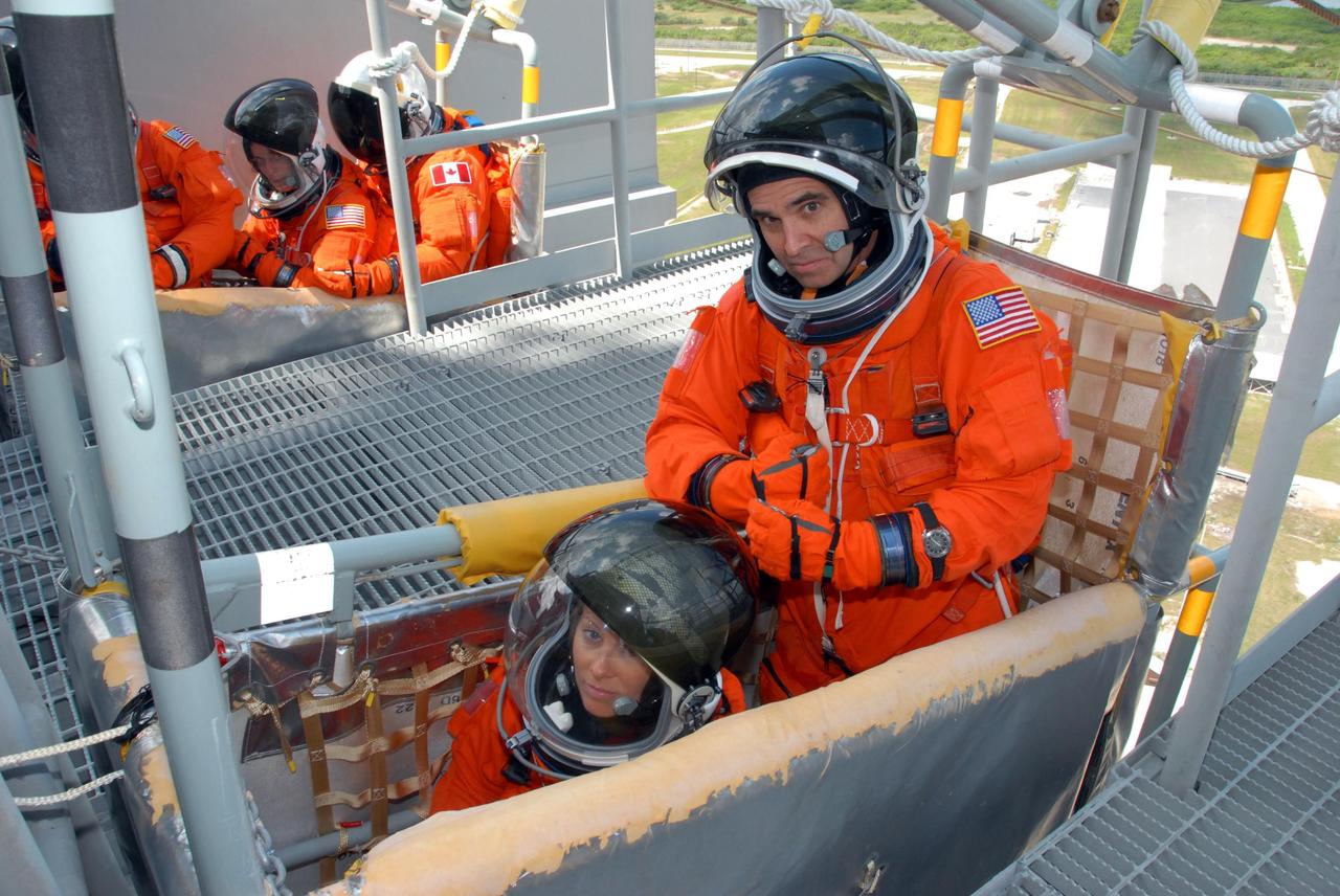 KENNEDY SPACE CENTER, Fla.  --  Practicing emergency egress from Launch Pad 39A, STS-118 Mission Specialists Tracy Caldwell (left) and Rick Mastracchio are seated in a slidewire basket in the foreground.  Others in the background include Mission Specialist Barbara R. Morgan (center).  Other crew members are Commander Scott Kelly, Pilot Charlie Hobaugh and Mission Specialists Dave Williams and Alvin Drew. Morgan joined NASA's Teacher in Space program in 1985 and was selected as an astronaut in 1998.  Williams represents the Canadian Space Agency. The STS-118 mission on Space Shuttle Endeavour is the 22nd flight to the International Space Station and will carry a payload including the S5 truss, a SPACEHAB module and external stowage platform 3. STS-118 is targeted for launch on Aug. 7.  Photo credit:  NASA/George Shelton