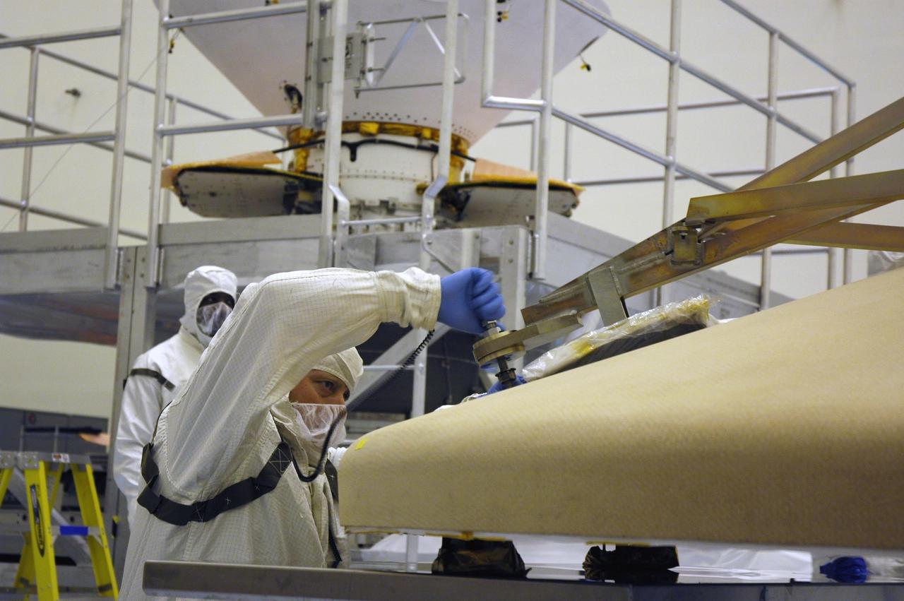 KENNEDY SPACE CENTER, Fla. -- In the Payload Hazardous Servicing Facility, workers attach a crane to the heat shield for the Phoenix Mars Lander spacecraft. The crane will lift and move the heat shield for installation over the lander within the cruise stage. Targeted for launch from Cape Canaveral Air Force Station on Aug. 3, Phoenix will land in icy soils near the north polar permanent ice cap of Mars and explore the history of the water in these soils and any associated rocks, while monitoring polar climate. Landing on Mars is planned in May 2008 on arctic ground where a mission currently in orbit, Mars Odyssey, has detected high concentrations of ice just beneath the top layer of soil. Photo credit: NASA/Troy Cryder