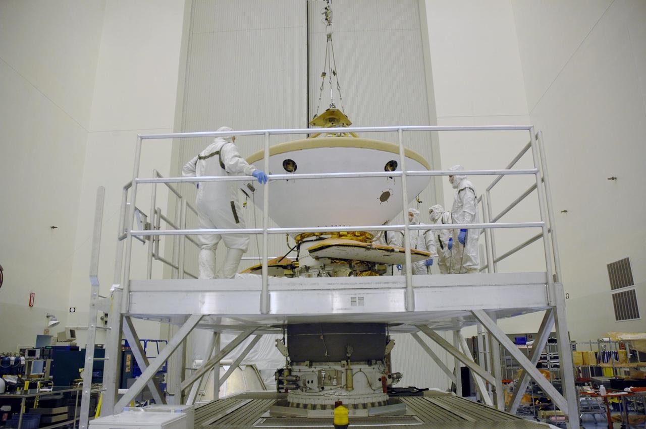 KENNEDY SPACE CENTER, Fla. -- In the Payload Hazardous Servicing Facility, workers observe the installation of the heat shield onto the Phoenix Mars Lander spacecraft. Targeted for launch from Cape Canaveral Air Force Station on Aug. 3, Phoenix will land in icy soils near the north polar permanent ice cap of Mars and explore the history of the water in these soils and any associated rocks, while monitoring polar climate. Landing on Mars is planned in May 2008 on arctic ground where a mission currently in orbit, Mars Odyssey, has detected high concentrations of ice just beneath the top layer of soil. Photo credit: NASA/Troy Cryder