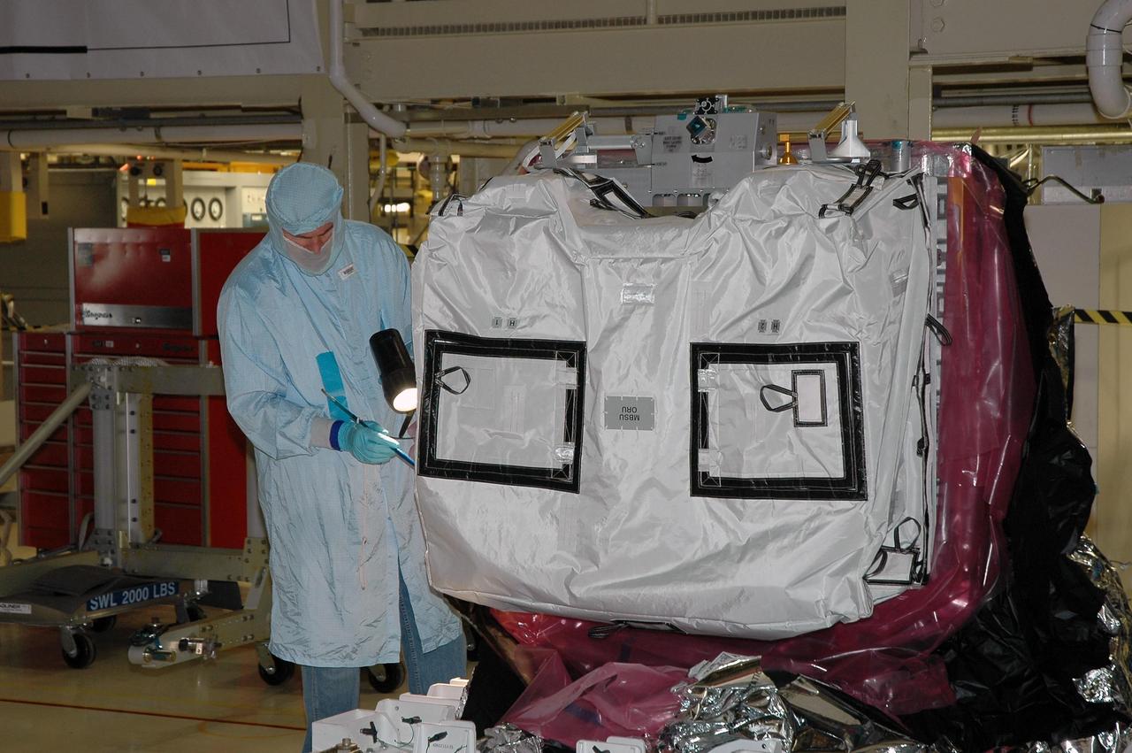 KENNEDY SPACE CENTER, Fla.  --  In the Orbiter Processing Facility bay 3, a worker checks the cover on a main bus switching unit, part of the payload on mission STS-120. A main bus switching unit is used for power distribution, circuit protection and fault isolation on the space station's power system.  The units route power to proper locations in the space station, such as from solar arrays through umbilicals into the U.S. Lab.  The unit will be installed on the external stowage platform 2 attached to the Quest airlock for temporary storage.  Discovery is targeted to launch mission STS-120 no earlier than Oct. 20.  Photo credit: NASA/Jim Grossmann