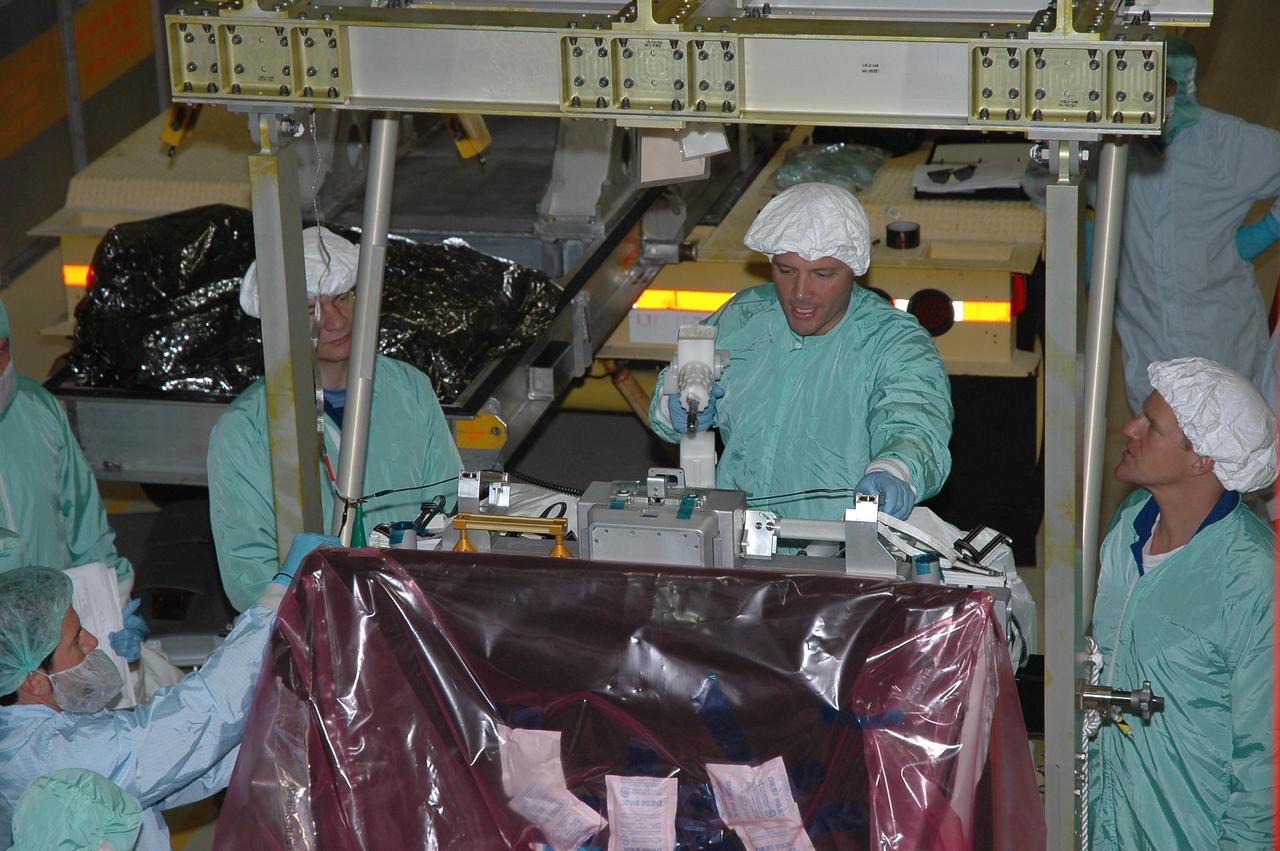 KENNEDY SPACE CENTER, Fla.  --  In the Orbiter Processing Facility bay 3, STS-120 crew members inspect the main bus switching unit that is part of the payload on their mission. From left are Mission Specialists Paolo Nespoli, Doug Wheelock and Scott Parazynski.  Wheelock is practicing using a tool on the unit.  Nespoli represents the European Space Agency.  A main bus switching unit is used for power distribution, circuit protection and fault isolation on the space station's power system.  The units route power to proper locations in the space station, such as from solar arrays through umbilicals into the U.S. Lab.  The unit will be installed on the external stowage platform 2 attached to the Quest airlock for temporary storage.  Discovery is targeted to launch mission STS-120 no earlier than Oct. 20.  Photo credit: NASA/Jim Grossmann