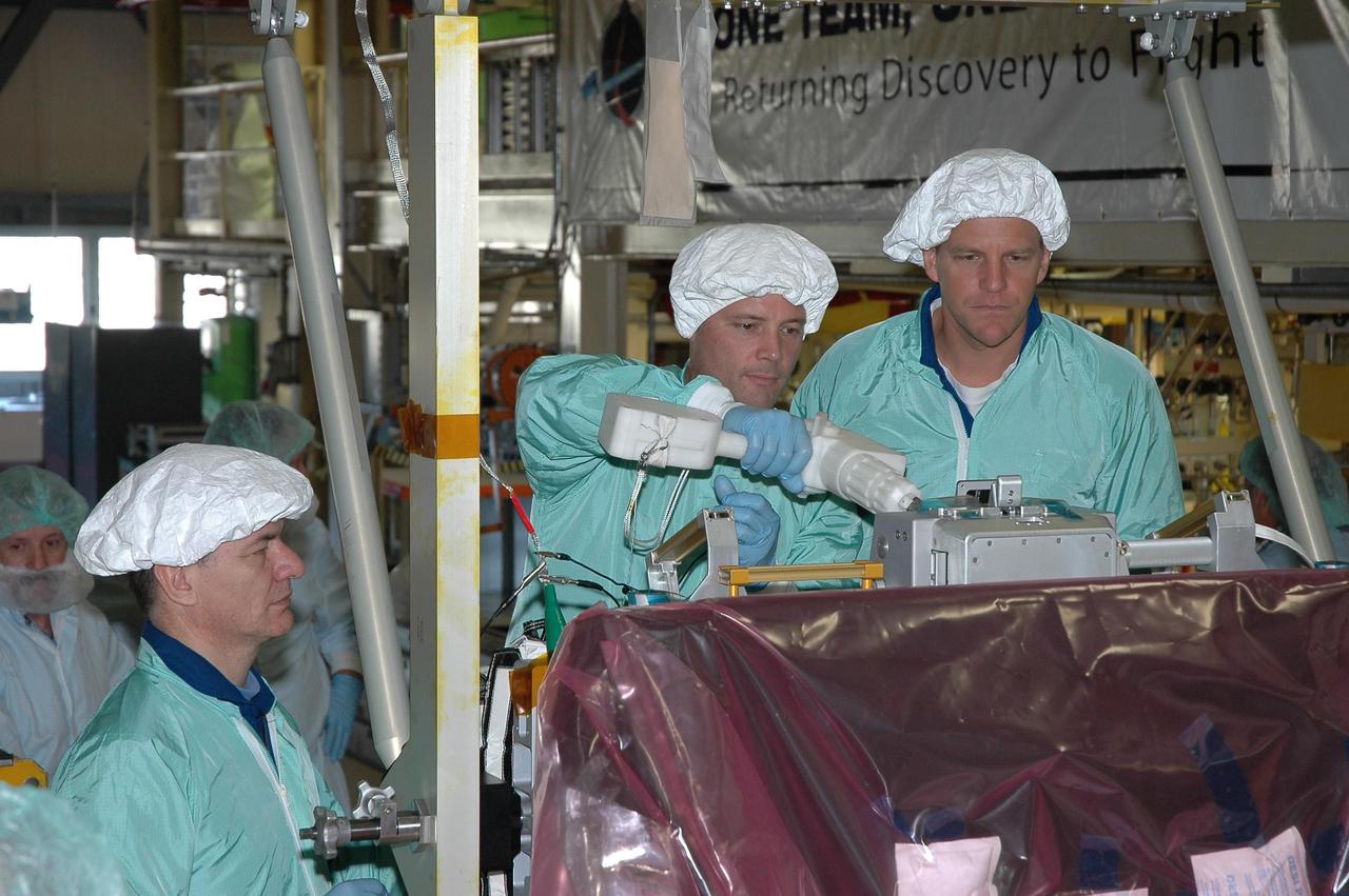 KENNEDY SPACE CENTER, Fla.  --  In the Orbiter Processing Facility bay 3, STS-120 crew members inspect the main bus switching unit that is part of the payload on their mission. From left are Mission Specialists Paolo Nespoli, Doug Wheelock and Scott Parazynski. Wheelock is practicing using a tool on the unit.   Nespoli represents the European Space Agency.  A main bus switching unit is used for power distribution, circuit protection and fault isolation on the space station's power system.  The units route power to proper locations in the space station, such as from solar arrays through umbilicals into the U.S. Lab.  The unit will be installed on the external stowage platform 2 attached to the Quest airlock for temporary storage.  Discovery is targeted to launch mission STS-120 no earlier than Oct. 20.  Photo credit: NASA/Jim Grossmann