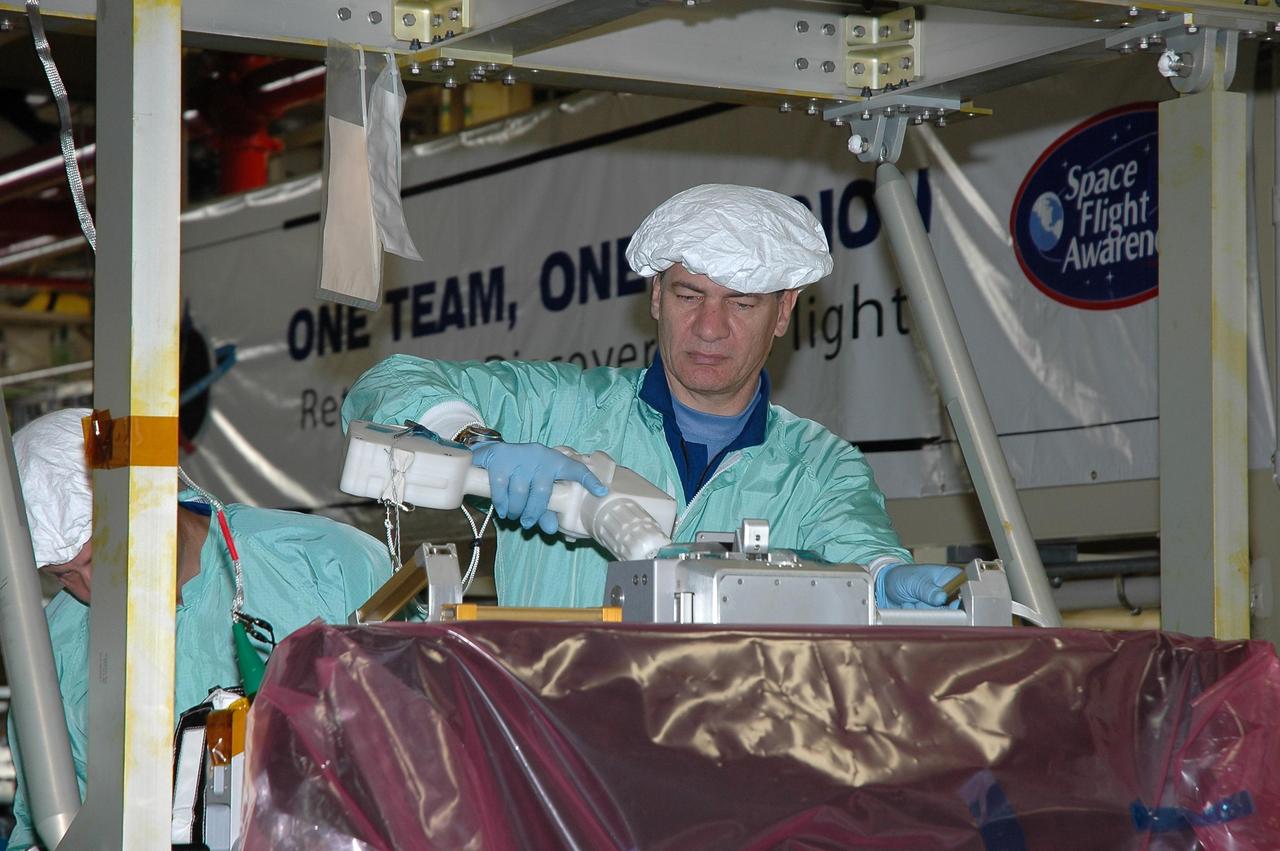 KENNEDY SPACE CENTER, Fla.  --  In the Orbiter Processing Facility bay 3, STS-120Mission Specialist Paolo Nespoli practices using a tool on the main bus switching unit that is part of the payload on the mission.  A main bus switching unit is used for power distribution, circuit protection and fault isolation on the space station's power system.  The units route power to proper locations in the space station, such as from solar arrays through umbilicals into the U.S. Lab.  The unit will be installed on the external stowage platform 2 attached to the Quest airlock for temporary storage.  Discovery is targeted to launch mission STS-120 no earlier than Oct. 20.  Photo credit: NASA/Jim Grossmann