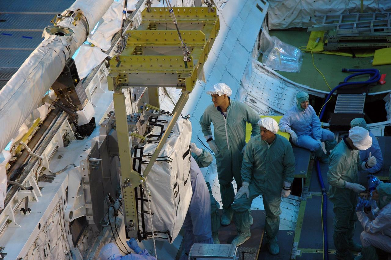 KENNEDY SPACE CENTER, Fla.  -- In the Orbiter Processing Facility bay 3, workers check the placement of a main bus switching unit in Discovery's payload bay.  A main bus switching unit is used for power distribution, circuit protection and fault isolation on the space station's power system.  The units route power to proper locations in the space station, such as from solar arrays through umbilicals into the U.S. Lab.  The unit will be installed on the external stowage platform 2 attached to the Quest airlock for temporary storage.  Discovery is targeted to launch mission STS-120 no earlier than Oct. 20.  Photo credit: NASA/Jim Grossmann
