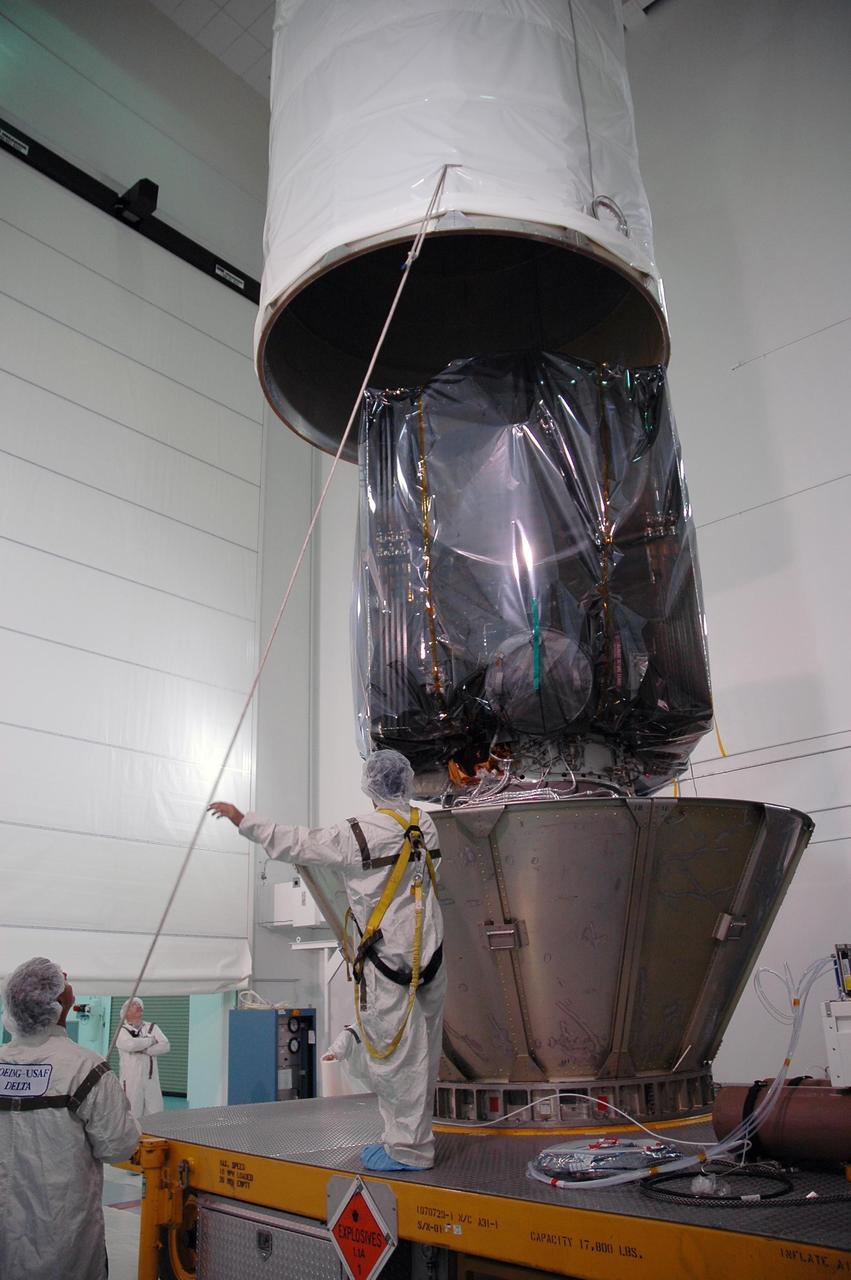 KENNEDY SPACE CENTER, FLA. —   At the Astrotech payload processing facility, workers guide the movement of the upper canister being lifted from the Dawn spacecraft, seen encased in a protective cover.  Dawn was returned from Launch Pad 17-B at Cape Canaveral Air Force Station to Astrotech to await a new launch date.  The launch opportunity extends from Sept. 7 to Oct. 15. Dawn is the ninth mission in NASA's Discovery Program. The spacecraft will be the first to orbit two planetary bodies, asteroid Vesta and dwarf planet Ceres,  during a single mission. Vesta and Ceres lie in the asteroid belt between Mars and Jupiter. It is also NASA’s first purely scientific mission powered by three solar electric ion propulsion engines.  NASA/Charisse Nahser