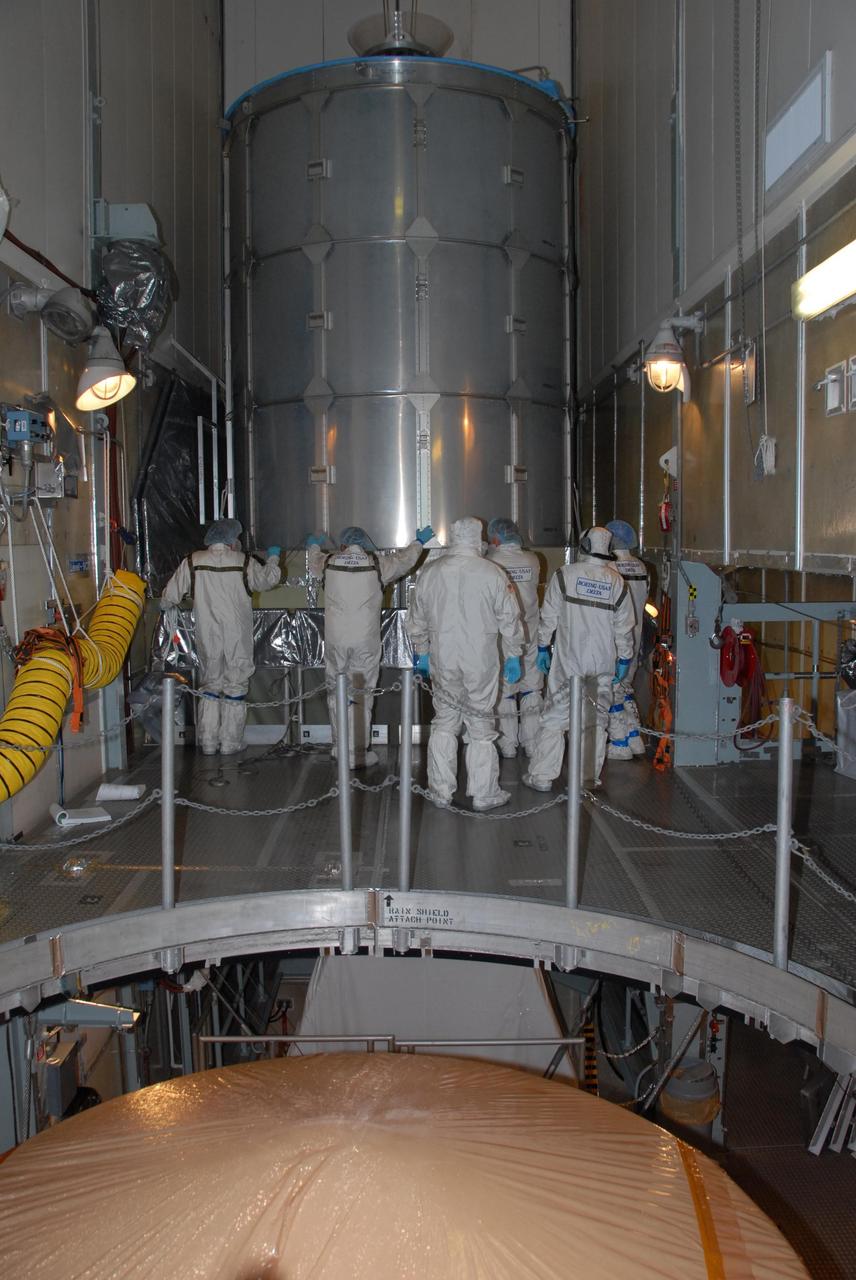 KENNEDY SPACE CENTER, FLA. -- Inside the mobile service tower of Launch Pad 17-A at Cape Canaveral Air Force Station in Florida, workers move the canister lid away from NASA's Phoenix Mars Lander, visible in the foreground. Phoenix is scheduled to launch on the Delta II launch vehicle no earlier than Aug. 3. Phoenix will land in icy soils near the north polar permanent ice cap of Mars and explore the history of the water in these soils and any associated rocks, while monitoring polar climate. Landing on Mars is planned in May 2008 on arctic ground where a mission currently in orbit, Mars Odyssey, detected high concentrations of ice just beneath the top layer of soil. NASA/George Shelton