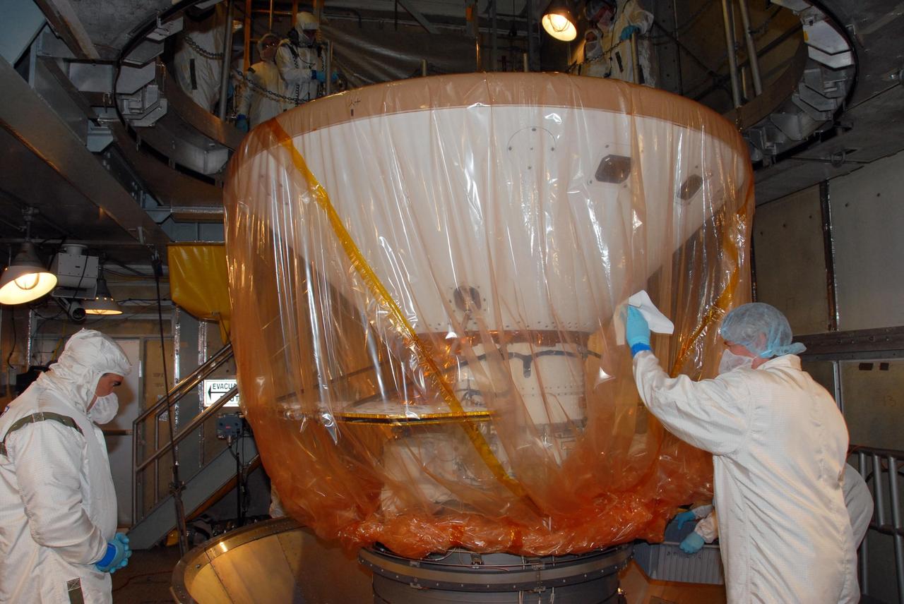 KENNEDY SPACE CENTER, FLA. -- Inside the mobile service tower of Launch Pad 17-A at Cape Canaveral Air Force Station in Florida, workers begin to remove the plastic covering from NASA's Phoenix Mars Lander. Phoenix is scheduled to launch on the Delta II launch vehicle no earlier than Aug. 3. Phoenix will land in icy soils near the north polar permanent ice cap of Mars and explore the history of the water in these soils and any associated rocks, while monitoring polar climate. Landing on Mars is planned in May 2008 on arctic ground where a mission currently in orbit, Mars Odyssey, detected high concentrations of ice just beneath the top layer of soil. NASA/George Shelton