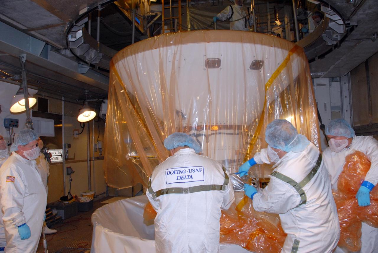 KENNEDY SPACE CENTER, FLA. -- Inside the mobile service tower of Launch Pad 17-A at Cape Canaveral Air Force Station in Florida, workers begin to remove the plastic covering from NASA's Phoenix Mars Lander. Phoenix is scheduled to launch on the Delta II launch vehicle no earlier than Aug. 3. Phoenix will land in icy soils near the north polar permanent ice cap of Mars and explore the history of the water in these soils and any associated rocks, while monitoring polar climate. Landing on Mars is planned in May 2008 on arctic ground where a mission currently in orbit, Mars Odyssey, detected high concentrations of ice just beneath the top layer of soil. NASA/George Shelton