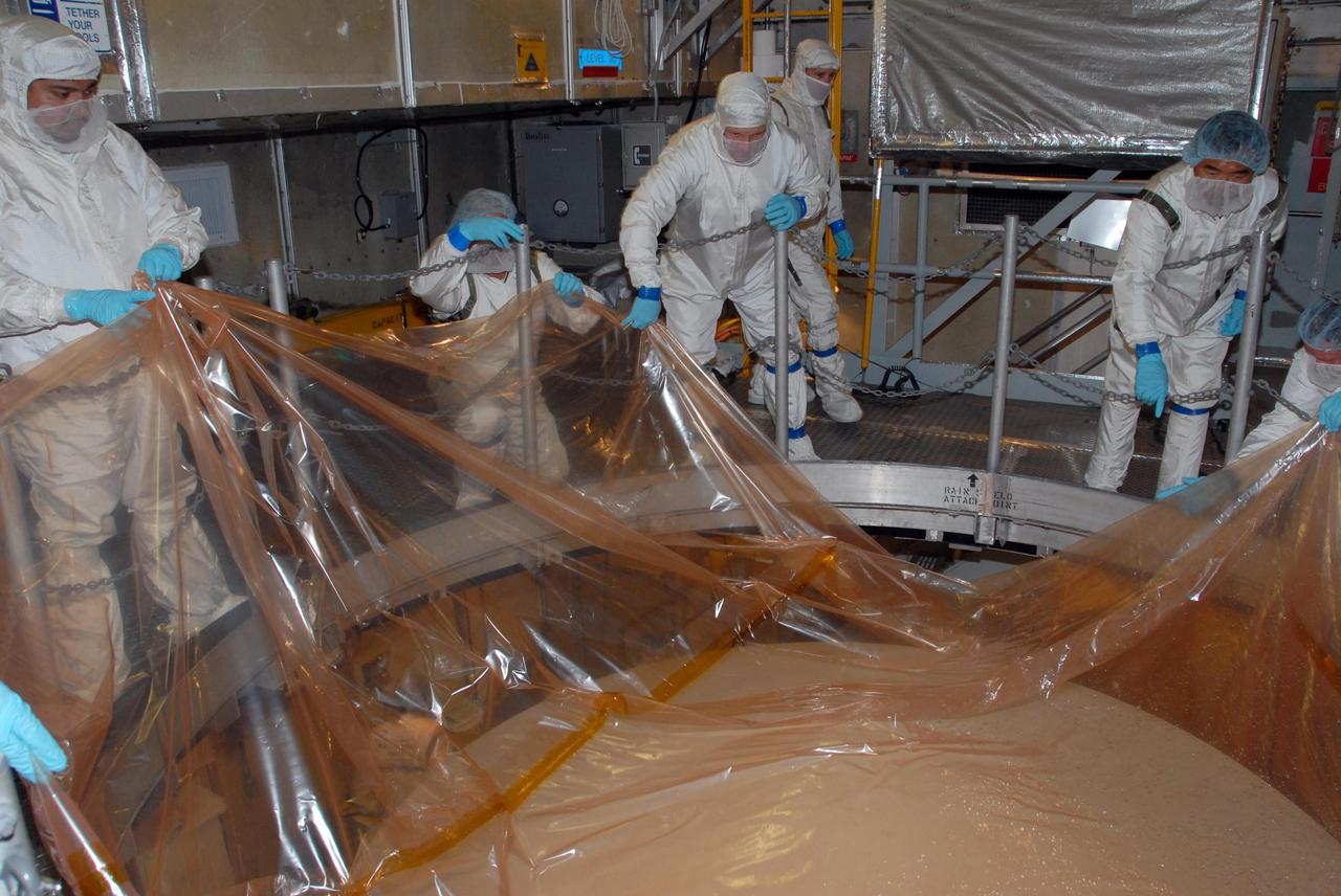 KENNEDY SPACE CENTER, FLA. -- Inside the mobile service tower of Launch Pad 17-A at Cape Canaveral Air Force Station in Florida, workers begin to remove the plastic covering from NASA's Phoenix Mars Lander. Phoenix is scheduled to launch on the Delta II launch vehicle no earlier than Aug. 3. Phoenix will land in icy soils near the north polar permanent ice cap of Mars and explore the history of the water in these soils and any associated rocks, while monitoring polar climate. Landing on Mars is planned in May 2008 on arctic ground where a mission currently in orbit, Mars Odyssey, detected high concentrations of ice just beneath the top layer of soil. NASA/George Shelton