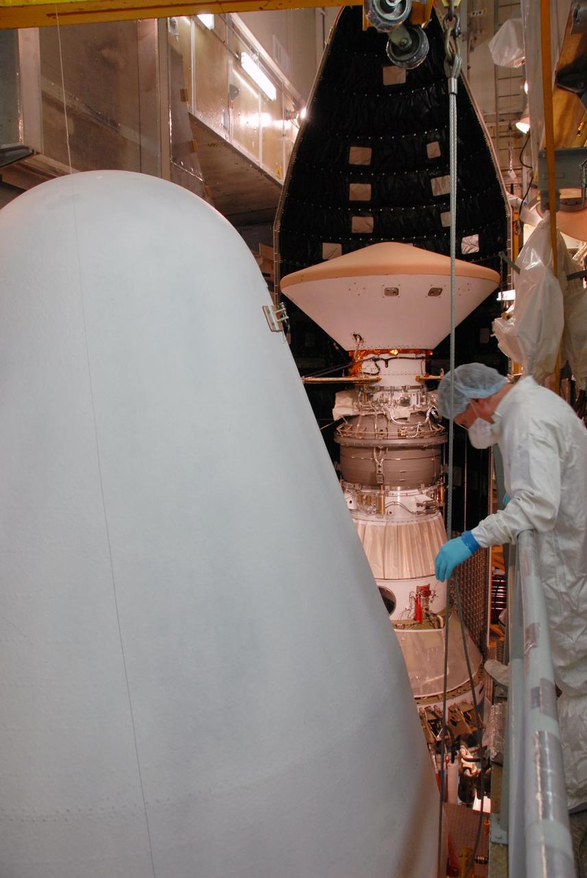 KENNEDY SPACE CENTER, FLA. --    On Launch Pad 17-A at Cape Canaveral Air Force Station, the second half of the fairing (in the foreground) moves toward the Phoenix Mars Lander for installation.  Phoenix is targeted for launch on Aug. 3 aboard a Delta II rocket.  The fairing is a molded structure that fits flush with the outside surface of the Delta II upper stage booster and forms an aerodynamically smooth nose cone, protecting the spacecraft during launch and ascent.  Phoenix will land in icy soils near the north polar, permanent ice cap of Mars and explore the history of the water in these soils and any associated rocks, while monitoring polar climate. Landing on Mars is planned in May 2008 on arctic ground where a mission currently in orbit, Mars Odyssey, has detected high concentrations of ice just beneath the top layer of soil.  NASA/George Shelton