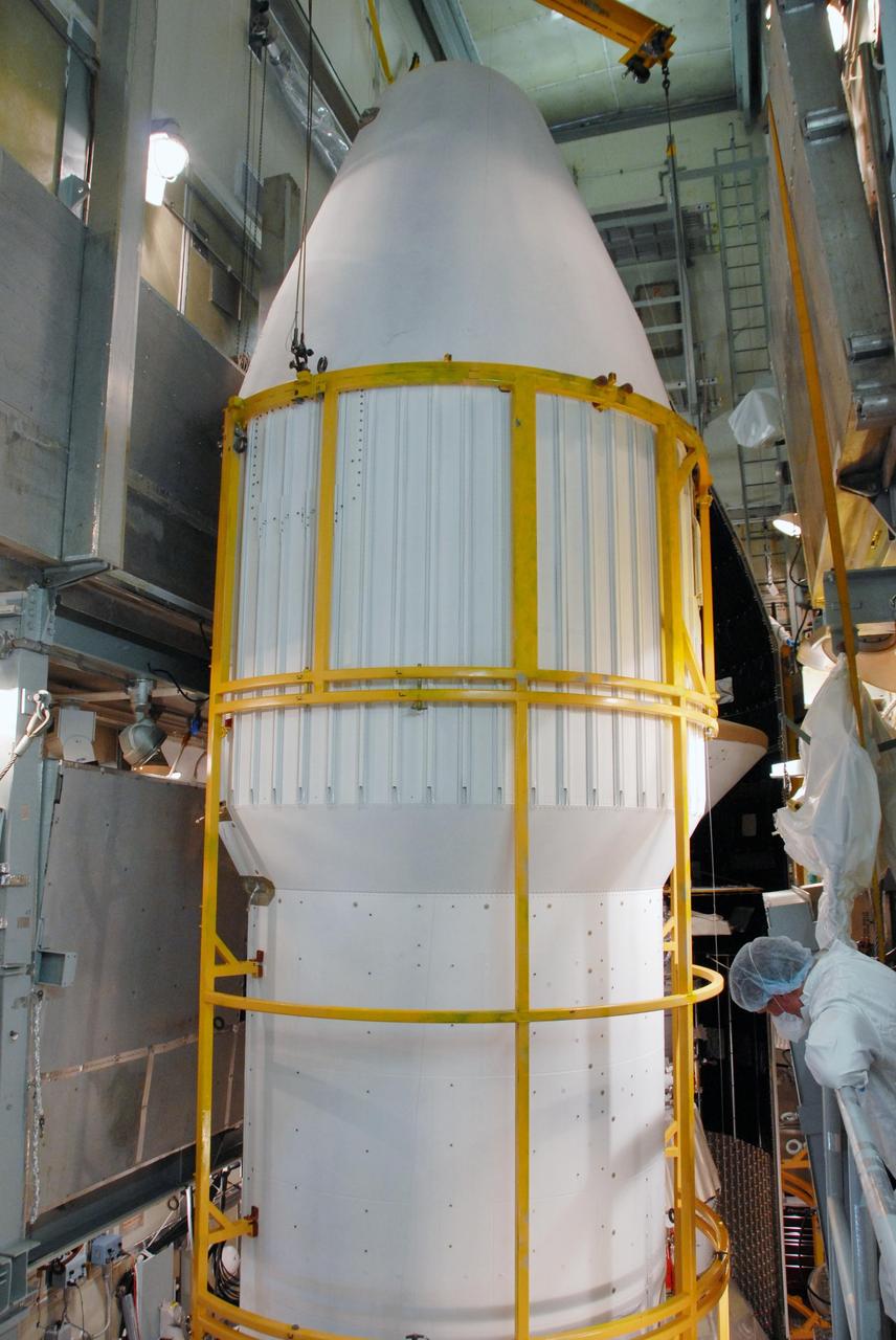 KENNEDY SPACE CENTER, FLA. -- On Launch Pad 17-A at Cape Canaveral Air Force Station, the second half of the fairing (in the foreground) moves closer to the Phoenix Mars Lander for installation toward the first half. Phoenix is targeted for launch on Aug. 3 aboard a Delta II rocket. The fairing is a molded structure that fits flush with the outside surface of the Delta II upper stage booster and forms an aerodynamically smooth nose cone, protecting the spacecraft during launch and ascent. Phoenix will land in icy soils near the north polar, permanent ice cap of Mars and explore the history of the water in these soils and any associated rocks, while monitoring polar climate. Landing on Mars is planned in May 2008 on arctic ground where a mission currently in orbit, Mars Odyssey, has detected high concentrations of ice just beneath the top layer of soil. NASA/George Shelton