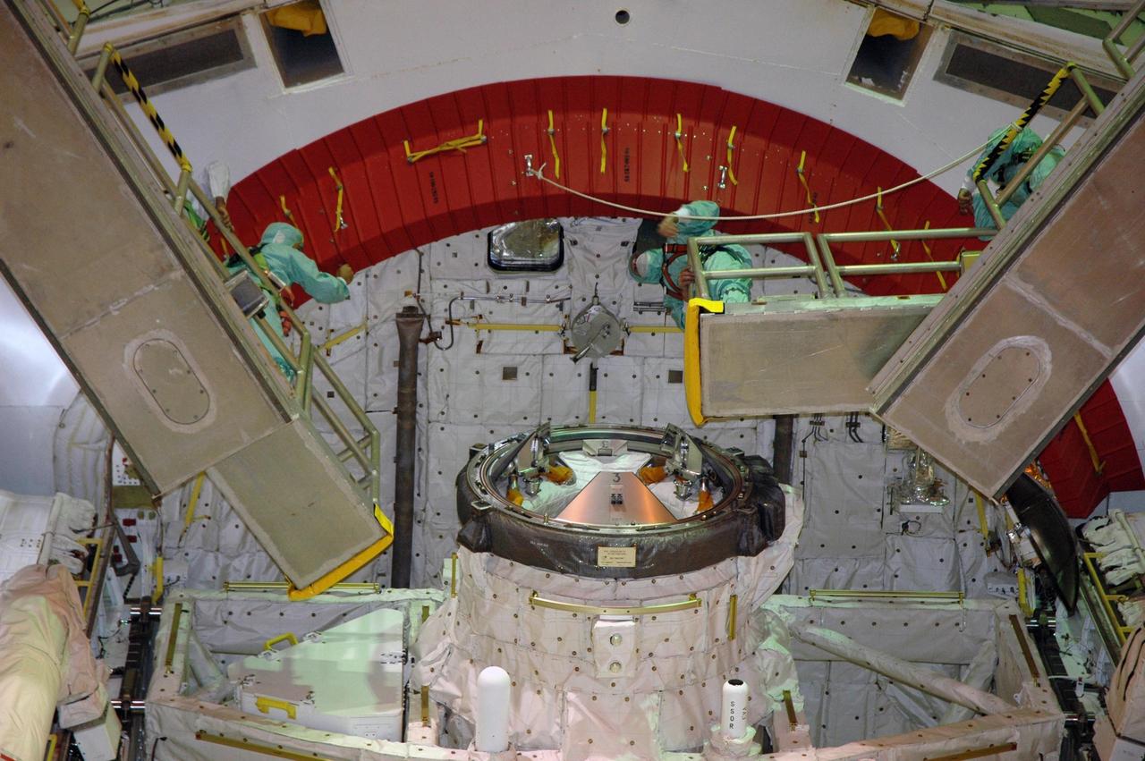 KENNEDY SPACE CENTER, FLA. -- Looking into the open payload bay doors of Space Shuttle Endeavour, workers conclude closeouts. At center foreground is the orbital docking system. The red ring at top comprises rain gutters to prevent leaks into the bay from rain while the shuttle is on the pad. The payload bay doors were opened to allow for payload closeouts, including camera tests on the shuttle robotic arm and the extension, known as the orbiter boom sensor system. Endeavour is scheduled to launch Aug. 7 on mission STS-118, the 22nd flight to the International Space Station. NASA/Charisse Nahser