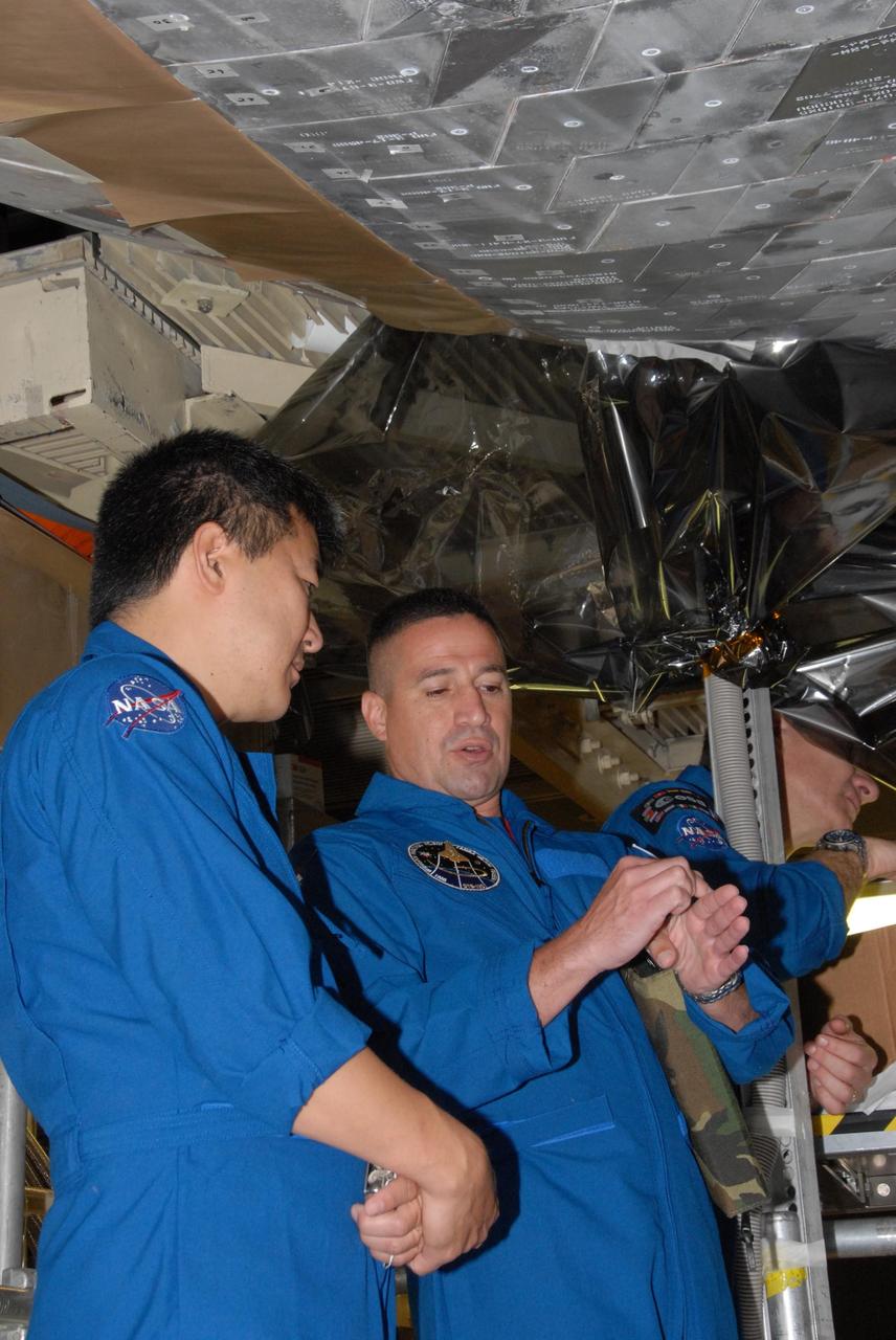 KENNEDY SPACE CENTER, FLA. - The STS-120 crew is at Kennedy for a crew equipment interface test, or CEIT.  Standing under space shuttle Discovery in Orbiter Processing Facility bay 3, from left, are Expedition 16 Flight Engineer Daniel M. Tani, Pilot George D. Zamka and Mission Specialist Paolo A. Nespoli, a European Space Agency astronaut from Italy. Among the activities standard to a CEIT are harness training, inspection of the thermal protection system and camera operation for planned extravehicular activities, or EVAs. The STS-120 mission will deliver the Harmony module, christened after a school contest, which will provide attachment points for European and Japanese laboratory modules on the International Space Station. Known in technical circles as Node 2, it is similar to the six-sided Unity module that links the U.S. and Russian sections of the station. Built in Italy for the United States, Harmony will be the first new U.S. pressurized component to be added.  The STS-120 mission is targeted to launch on Oct. 20.  Photo credit:  NASA/George Shelton