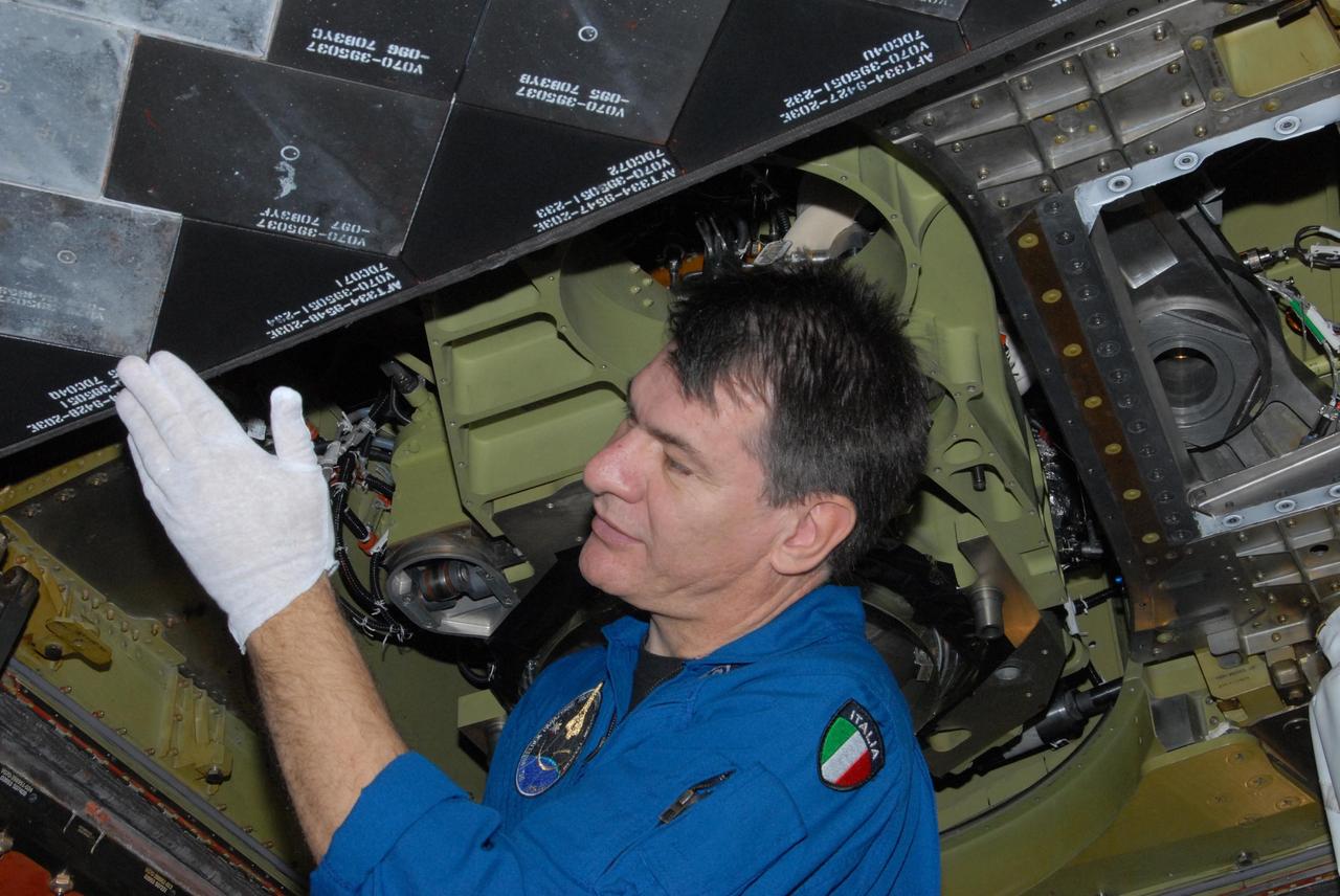 KENNEDY SPACE CENTER, FLA. - The STS-120 crew is at Kennedy for a crew equipment interface test, or CEIT.  Inspecting the thermal protection system, or TPS, tiles under space shuttle Discovery in Orbiter Processing Facility bay 3 is Mission Specialist Paolo A. Nespoli, a European Space Agency astronaut from Italy.  Among the activities standard to a CEIT are harness training, inspection of the thermal protection system and camera operation for planned extravehicular activities, or EVAs. The STS-120 mission will deliver the Harmony module, christened after a school contest, which will provide attachment points for European and Japanese laboratory modules on the International Space Station. Known in technical circles as Node 2, it is similar to the six-sided Unity module that links the U.S. and Russian sections of the station. Built in Italy for the United States, Harmony will be the first new U.S. pressurized component to be added.  The STS-120 mission is targeted to launch on Oct. 20.  Photo credit:  NASA/George Shelton