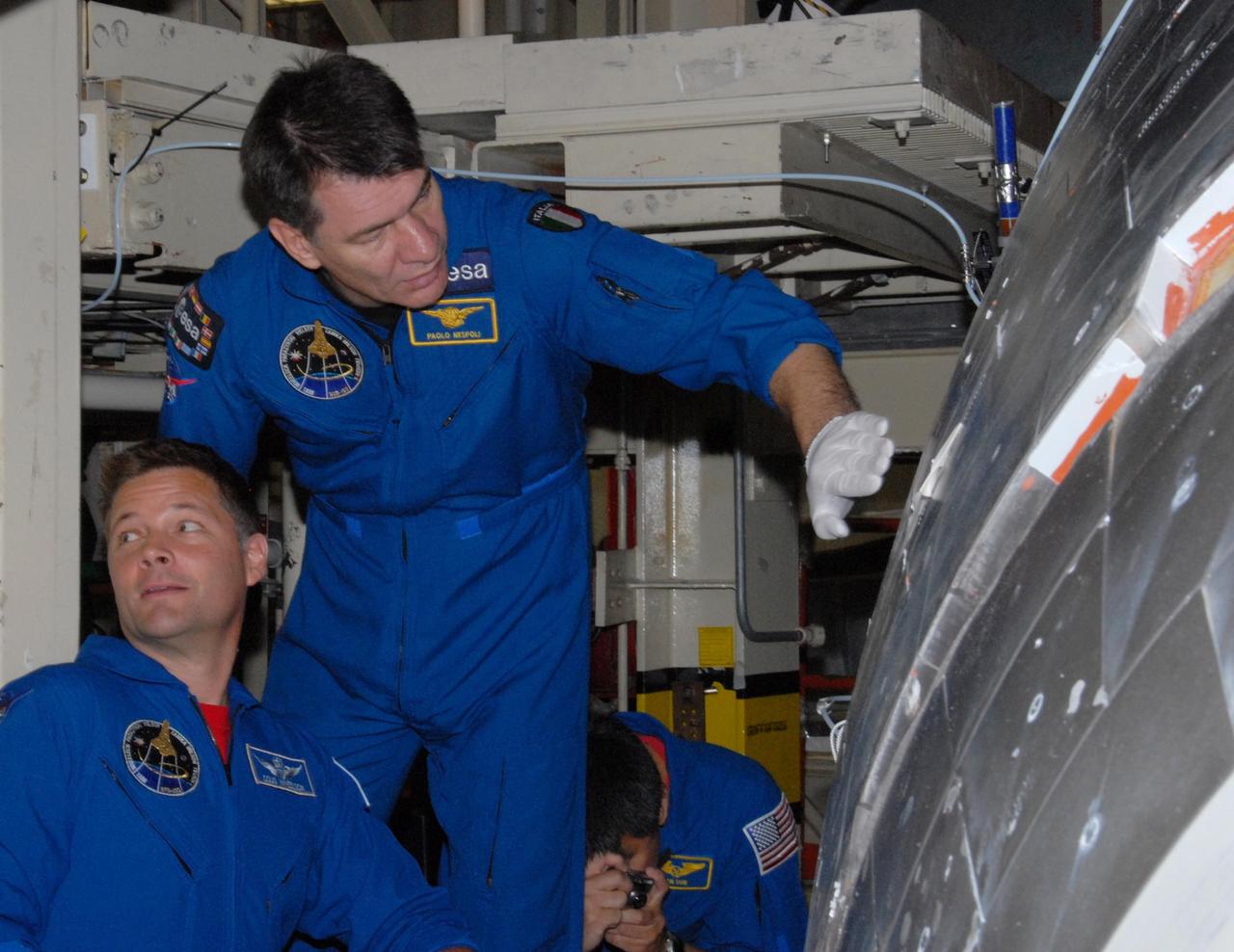 KENNEDY SPACE CENTER, FLA. - The STS-120 crew is at Kennedy for a crew equipment interface test, or CEIT.  Inspecting the thermal protection system, or TPS, tiles on space shuttle Discovery in Orbiter Processing Facility bay 3 are Mission Specialists Douglas H. Wheelock and Paolo A. Nespoli, a European Space Agency astronaut from Italy, and Expedition 16 Flight Engineer Daniel M. Tani (with camera).  Among the activities standard to a CEIT are harness training, inspection of the thermal protection system and camera operation for planned extravehicular activities, or EVAs. The STS-120 mission will deliver the Harmony module, christened after a school contest, which will provide attachment points for European and Japanese laboratory modules on the International Space Station. Known in technical circles as Node 2, it is similar to the six-sided Unity module that links the U.S. and Russian sections of the station. Built in Italy for the United States, Harmony will be the first new U.S. pressurized component to be added.  The STS-120 mission is targeted to launch on Oct. 20. Photo credit:   NASA/George Shelton