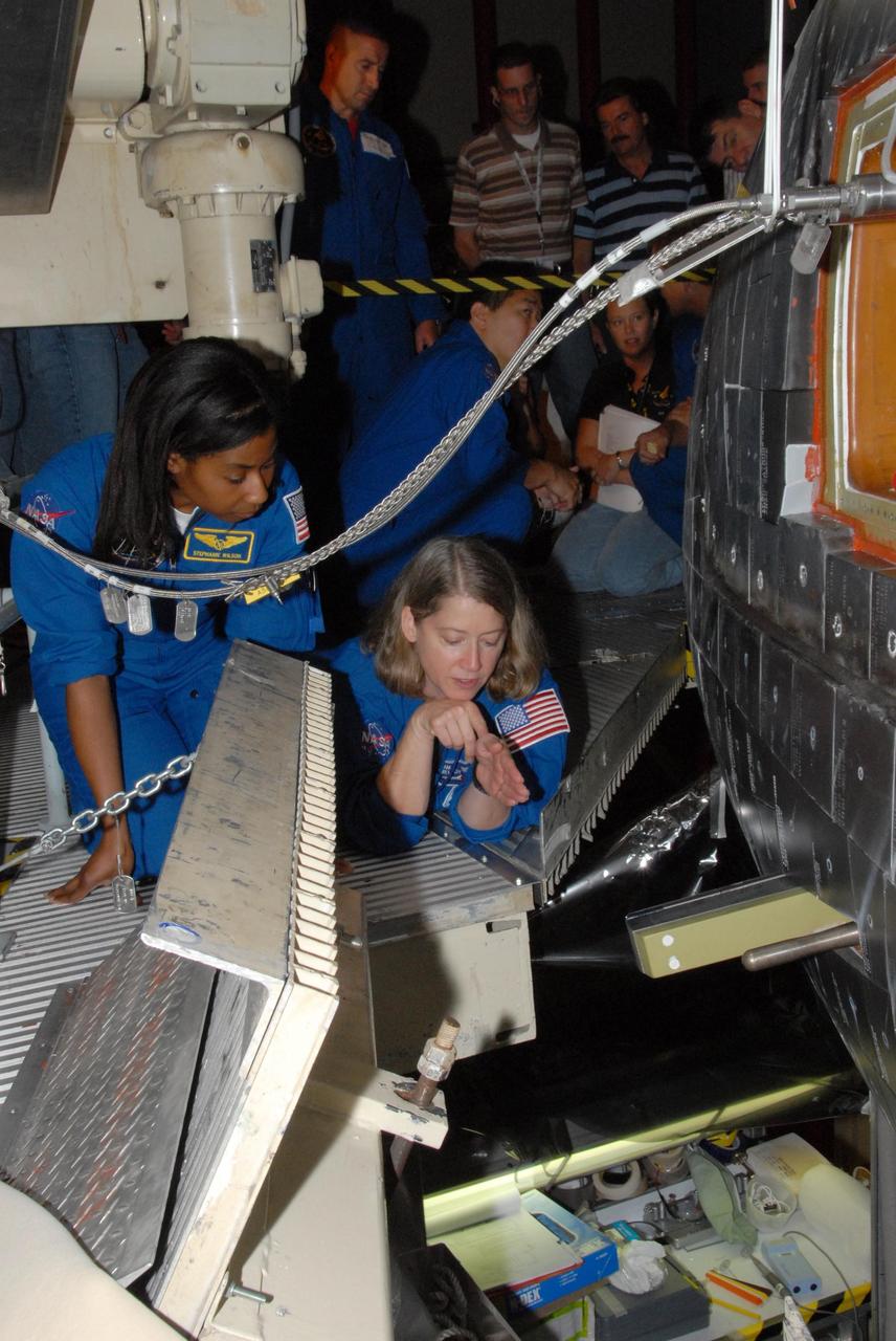 KENNEDY SPACE CENTER, FLA. - The STS-120 crew is at Kennedy for a crew equipment interface test, or CEIT.  Giving a close inspection to space shuttle Discovery in Orbiter Processing Facility bay 3 are Mission Specialist Stephanie D. Wilson and Commander Pamela A. Melroy.  Among the activities standard to a CEIT are harness training, inspection of the thermal protection system and camera operation for planned extravehicular activities, or EVAs. The STS-120 mission will deliver the Harmony module, christened after a school contest, which will provide attachment points for European and Japanese laboratory modules on the International Space Station. Known in technical circles as Node 2, it is similar to the six-sided Unity module that links the U.S. and Russian sections of the station. Built in Italy for the United States, Harmony will be the first new U.S. pressurized component to be added.  The STS-120 mission is targeted to launch on Oct. 20.  Photo credit: NASA/George Shelton