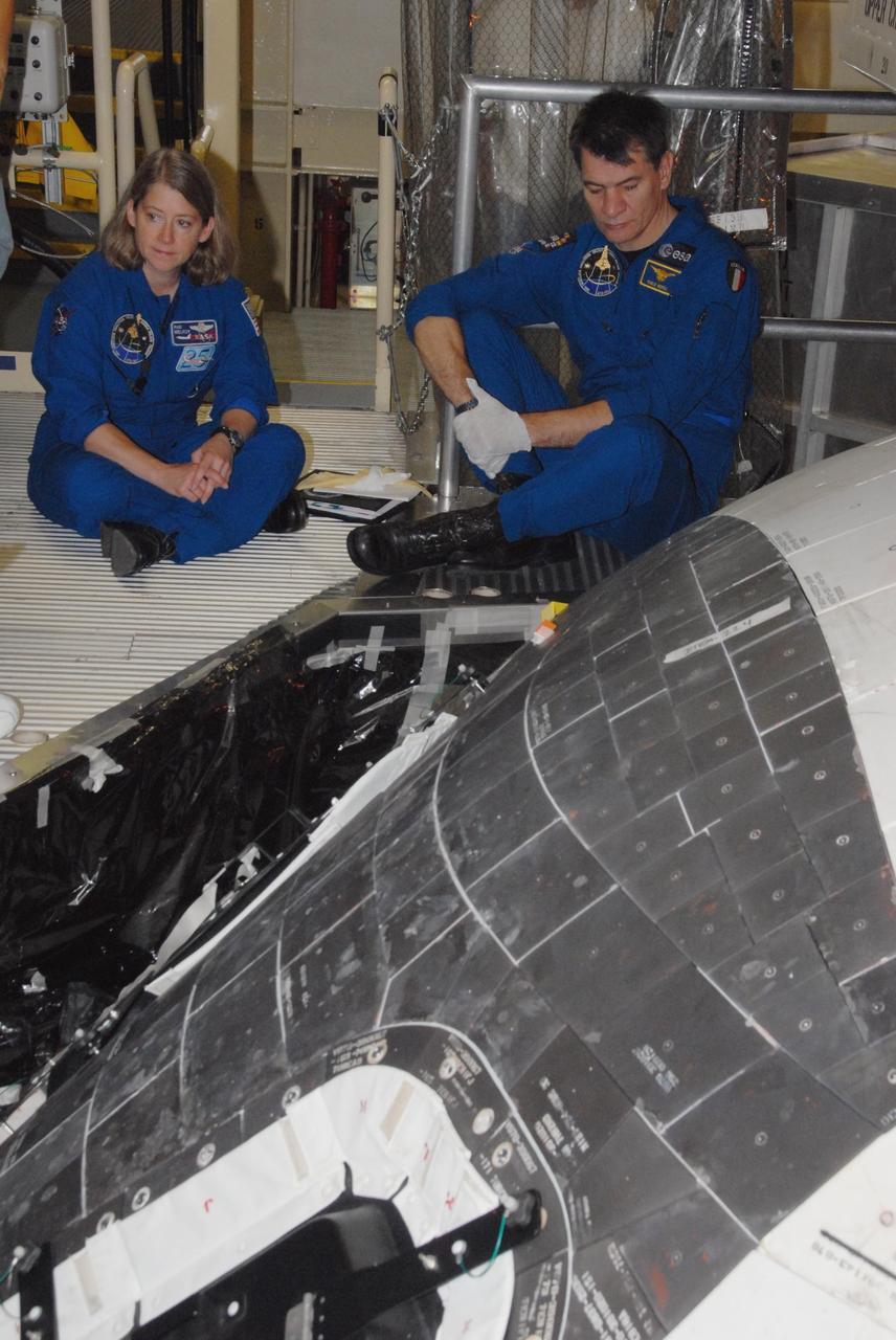 KENNEDY SPACE CENTER, FLA. - The STS-120 crew is at Kennedy for a crew equipment interface test, or CEIT.  Receiving a briefing on the thermal protection system, or TPS, tiles on space shuttle Discovery in Orbiter Processing Facility bay 3 are Commander Pamela A. Melroy and Mission Specialist Paolo A. Nespoli, a European Space Agency astronaut from Italy.  Among the activities standard to a CEIT are harness training, inspection of the thermal protection system and camera operation for planned extravehicular activities, or EVAs. The STS-120 mission will deliver the Harmony module, christened after a school contest, which will provide attachment points for European and Japanese laboratory modules on the International Space Station. Known in technical circles as Node 2, it is similar to the six-sided Unity module that links the U.S. and Russian sections of the station. Built in Italy for the United States, Harmony will be the first new U.S. pressurized component to be added.  The STS-120 mission is targeted to launch on Oct. 20.  Photo credit: NASA/George Shelton