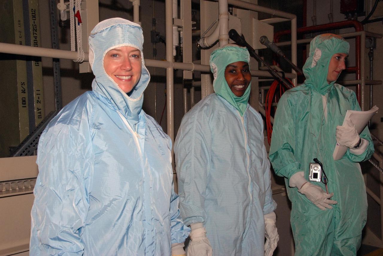 KENNEDY SPACE CENTER, FLA. - Dressed in clean-room suits are STS-120 Commander Pamela A. Melroy (left) and Mission Specialist Stephanie D. Wilson (center), getting ready to get into the bucket that will lower them into Discovery's payload bay in bay 3 of the Orbiter Processing Facility.   The STS-120 crew is at Kennedy for a crew equipment interface test, or CEIT, which includes harness training, inspection of the thermal protection system and camera operation for planned extravehicular activities, or EVAs. The STS-120 mission will deliver the Harmony module, christened after a school contest, which will provide attachment points for European and Japanese laboratory modules on the International Space Station. Known in technical circles as Node 2, it is similar to the six-sided Unity module that links the U.S. and Russian sections of the station. Built in Italy for the United States, Harmony will be the first new U.S. pressurized component to be added.  The STS-120 mission is targeted to launch on Oct. 20.  Photo credit: NASA/George Shelton