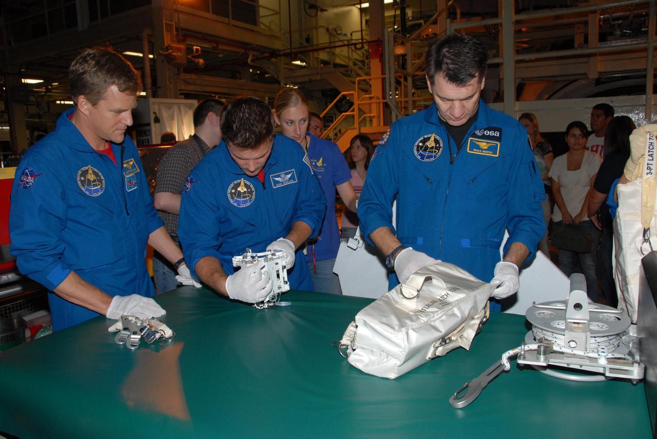KENNEDY SPACE CENTER, FLA. - In Orbiter Processing Facility bay 3, STS-120 Mission Specialists Scott E. Parazynski, Douglas H. Wheelock and Paolo A. Nespoli inspect tools they will use during the mission. Nespoli is a European Space Agency astronaut from Italy. Behind them is Allison Bolinger, an EVA technician with NASA. The STS-120 crew is at Kennedy for a crew equipment interface test, or CEIT, which includes harness training, inspection of the thermal protection system and camera operation for planned extravehicular activities, or EVAs. The STS-120 mission will deliver the Harmony module, christened after a school contest, which will provide attachment points for European and Japanese laboratory modules on the International Space Station. Known in technical circles as Node 2, it is similar to the six-sided Unity module that links the U.S. and Russian sections of the station. Built in Italy for the United States, Harmony will be the first new U.S. pressurized component to be added.  The STS-120 mission is targeted to launch on Oct. 20.  Photo credit: NASA/George Shelton