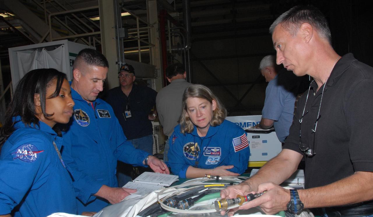 KENNEDY SPACE CENTER, FLA. - In Orbiter Processing Facility bay 3, STS-120 crew members practice handling tools they will use during the mission.  From left are Mission Specialist Stephanie D. Wilson, Pilot George D. Zamka and Commander Pamela A. Melroy.  The STS-120 crew is at Kennedy for a crew equipment interface test, or CEIT, which includes harness training, inspection of the thermal protection system and camera operation for planned extravehicular activities, or EVAs. The STS-120 mission will deliver the Harmony module, christened after a school contest, which will provide attachment points for European and Japanese laboratory modules on the International Space Station. Known in technical circles as Node 2, it is similar to the six-sided Unity module that links the U.S. and Russian sections of the station. Built in Italy for the United States, Harmony will be the first new U.S. pressurized component to be added.  The STS-120 mission is targeted to launch on Oct. 20.  Photo credit: NASA/George Shelton