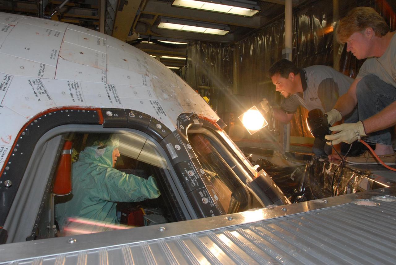 KENNEDY SPACE CENTER, FLA. - In the Orbiter Processing Facility bay 3, STS-120 Commander Pamela A. Melroy makes a close inspection of the cockpit window on the orbiter Discovery. The STS-120 crew is at Kennedy for a crew equipment interface test, or CEIT, which includes harness training, inspection of the thermal protection system and camera operation for planned extravehicular activities, or EVAs. The STS-120 mission will deliver the Harmony module, christened after a school contest, which will provide attachment points for European and Japanese laboratory modules on the International Space Station. Known in technical circles as Node 2, it is similar to the six-sided Unity module that links the U.S. and Russian sections of the station. Built in Italy for the United States, Harmony will be the first new U.S. pressurized component to be added.  The STS-120 mission is targeted to launch on Oct. 20.  Photo credit: NASA/George Shelton