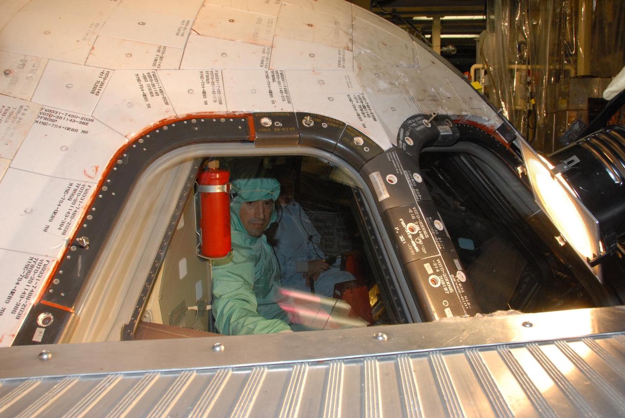 KENNEDY SPACE CENTER, FLA. - In the Orbiter Processing Facility bay 3, STS-120 Pilot George D. Zamka makes a close inspection of the cockpit window on the orbiter Discovery. Seated next to him is Commander Pamela A. Melroy. The STS-120 crew is at Kennedy for a crew equipment interface test, or CEIT, which includes harness training, inspection of the thermal protection system and camera operation for planned extravehicular activities, or EVAs. The STS-120 mission will deliver the Harmony module, christened after a school contest, which will provide attachment points for European and Japanese laboratory modules on the International Space Station. Known in technical circles as Node 2, it is similar to the six-sided Unity module that links the U.S. and Russian sections of the station. Built in Italy for the United States, Harmony will be the first new U.S. pressurized component to be added.  The STS-120 mission is targeted to launch on Oct. 20.  NASA/George Shelton