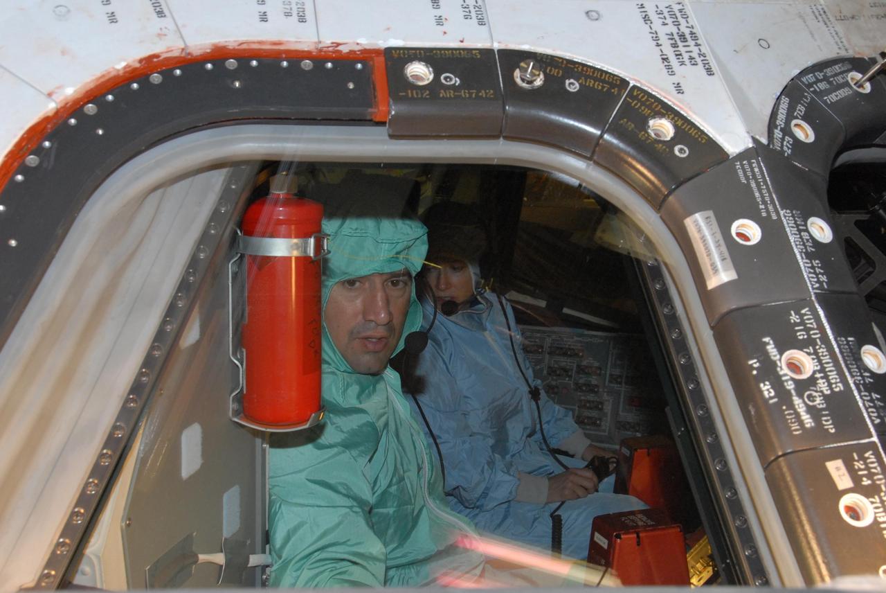 KENNEDY SPACE CENTER, FLA. - In the Orbiter Processing Facility bay 3, STS-120 Pilot George D. Zamka makes a close inspection of the cockpit window on the orbiter Discovery.  Seated next to him is Commander Pamela A. Melroy.  The STS-120 crew is at Kennedy for a crew equipment interface test, or CEIT, which includes harness training, inspection of the thermal protection system and camera operation for planned extravehicular activities, or EVAs. The STS-120 mission will deliver the Harmony module, christened after a school contest, which will provide attachment points for European and Japanese laboratory modules on the International Space Station. Known in technical circles as Node 2, it is similar to the six-sided Unity module that links the U.S. and Russian sections of the station. Built in Italy for the United States, Harmony will be the first new U.S. pressurized component to be added.  The STS-120 mission is targeted to launch on Oct. 20. Photo credit: NASA/George Shelton