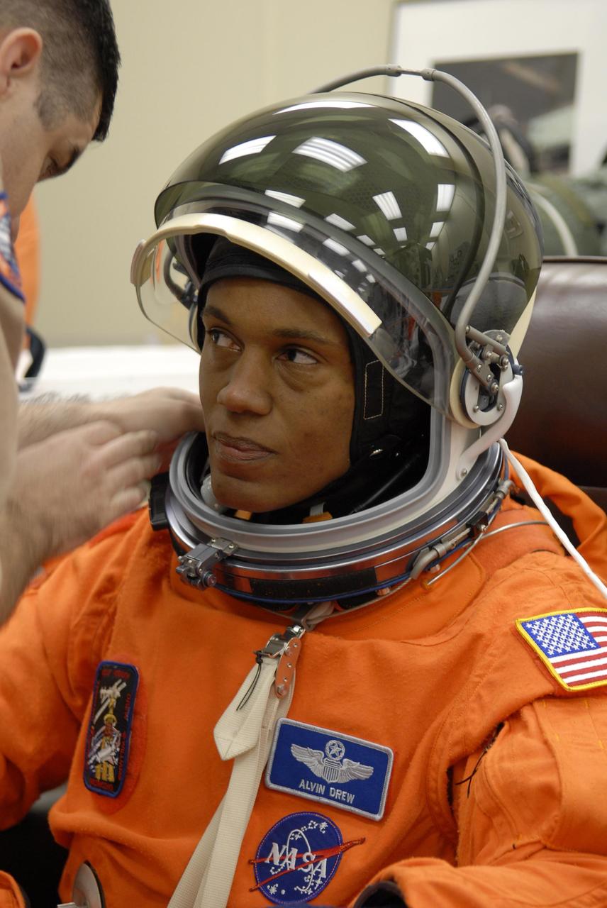 KENNEDY SPACE CENTER, FLA. --  In the Operations and Checkout Building, STS-118 Mission Specialist Alvin Drew is helped with his helmet during suitup for launch on Space Shuttle Endeavour.  The STS-118 mission is the 22nd shuttle flight to the International Space Station. It will continue space station construction by delivering a third starboard truss segment, S5, and other payloads such as the SPACEHAB module and the external stowage platform 3.  The 11-day mission may be extended to as many as 14 depending on the test of the Station-to-Shuttle Power Transfer System that will allow the docked shuttle to draw electrical power from the station and extend its visits to the orbiting lab.  NASA/Kim Shiflett