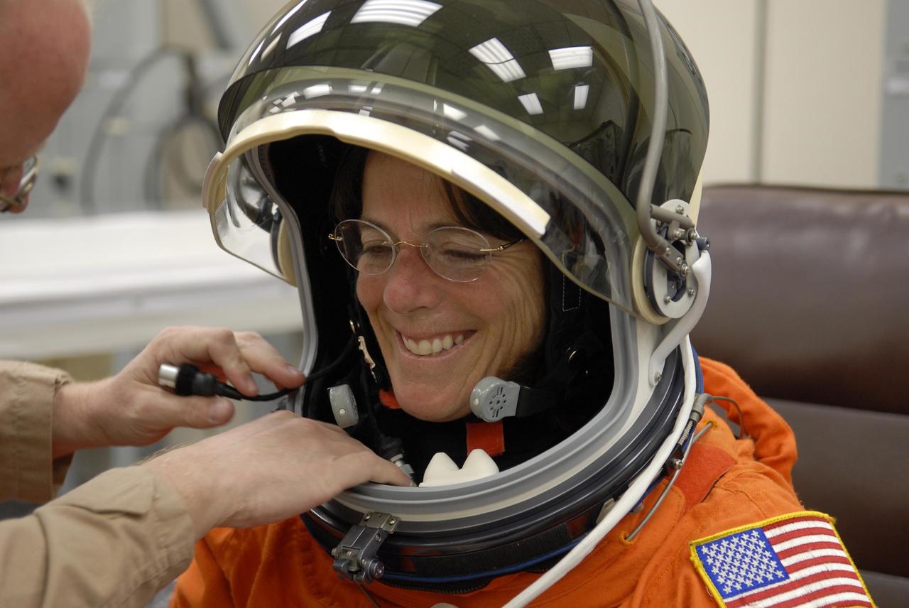 KENNEDY SPACE CENTER, FLA. --  In the Operations and Checkout Building during suitup, STS-118 Mission Specialist Barbara R. Morgan, teacher-turned-astronaut, is helped with her helmet for launch aboard Space Shuttle Endeavour. The STS-118 mission is the 22nd shuttle flight to the International Space Station. It will continue space station construction by delivering a third starboard truss segment, S5, and other payloads such as the SPACEHAB module and the external stowage platform 3.  The 11-day mission may be extended to as many as 14 depending on the test of the Station-to-Shuttle Power Transfer System that will allow the docked shuttle to draw electrical power from the station and extend its visits to the orbiting lab.  NASA/Kim Shiflett
