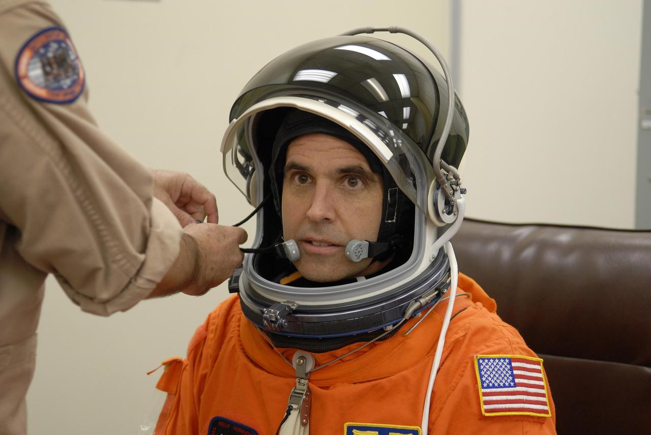 KENNEDY SPACE CENTER, FLA. --  In the Operations and Checkout Building, STS-118 Mission Specialist Rick Mastracchio is helped with his helmet during suitup before launch aboard Space Shuttle Endeavour.  Mastracchio is making his second spaceflight. The STS-118 mission is the 22nd shuttle flight to the International Space Station. It will continue space station construction by delivering a third starboard truss segment, S5, and other payloads such as the SPACEHAB module and the external stowage platform 3.  The 11-day mission may be extended to as many as 14 depending on the test of the Station-to-Shuttle Power Transfer System that will allow the docked shuttle to draw electrical power from the station and extend its visits to the orbiting lab.  NASA/Kim Shiflett