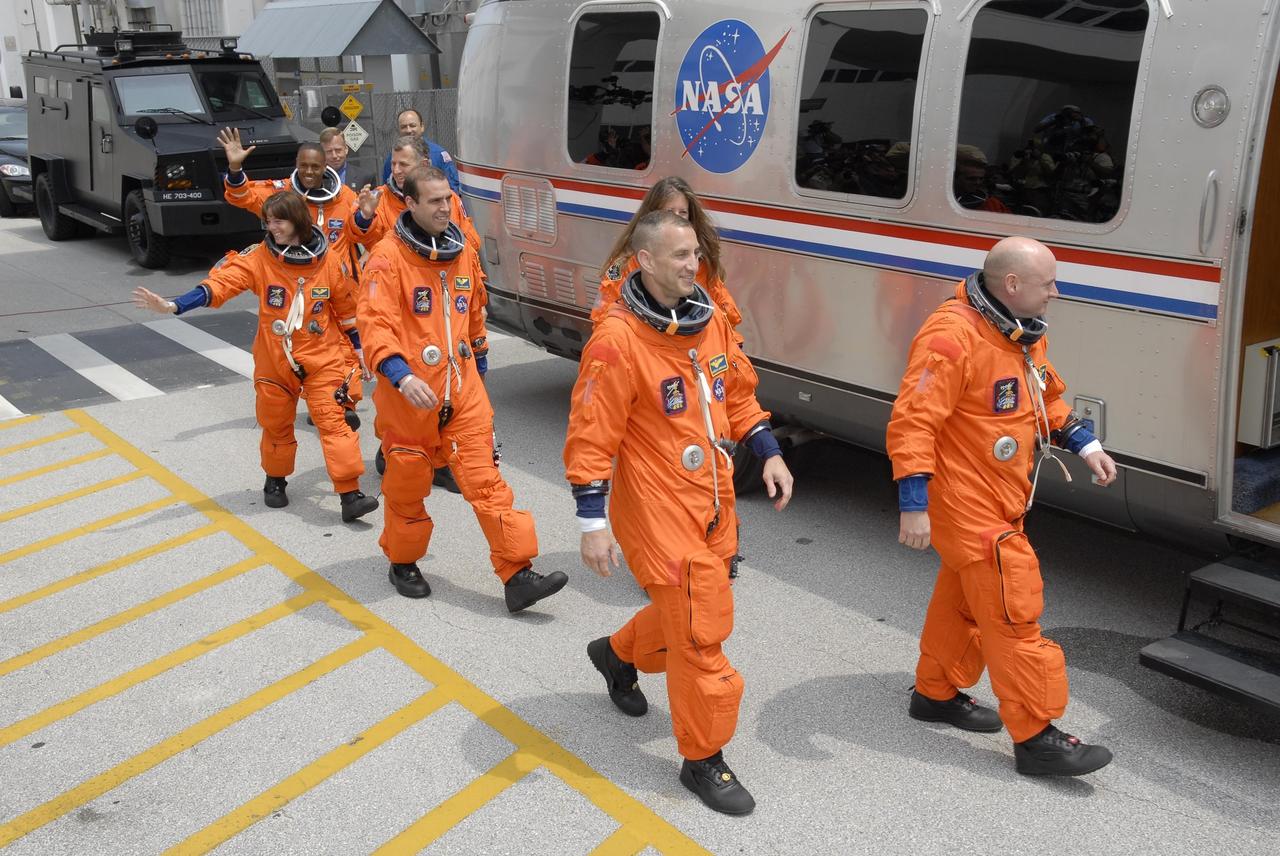 KENNEDY SPACE CENTER, FLA. --  The STS-118 crew waves to spectators as they head for the Astrovan.  From left are  Mission Specialists Alvin Drew, Barbara R. Morgan, Dave Williams and Rick Mastracchio, Pilot Charlie Hobaugh, Mission Specialist Tracy Caldwell and Commander Scott Kelly.  The Astrovan will take them to Launch Pad 39A for final suit preparations before climbing into Space Shuttle Endeavour for launch at 6:36 p.m. EDT. The STS-118 mission is the 22nd shuttle flight to the International Space Station. It will continue space station construction by delivering a third starboard truss segment, S5, and other payloads such as the SPACEHAB module and the external stowage platform 3.  The 11-day mission may be extended to as many as 14 depending on the test of the Station-to-Shuttle Power Transfer System that will allow the docked shuttle to draw electrical power from the station and extend its visits to the orbiting lab.  NASA/Kim Shiflett