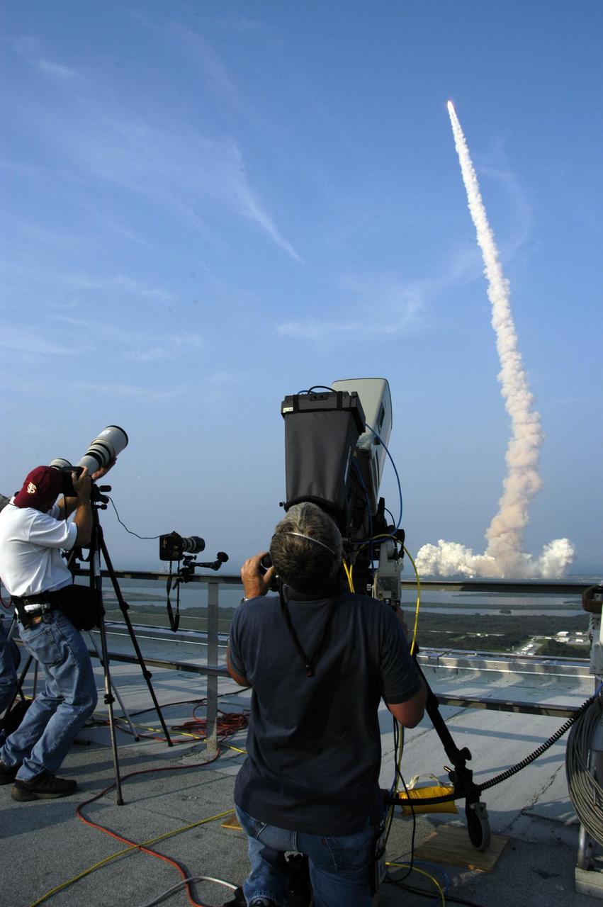KENNEDY SPACE CENTER, FLA. -- Photographers at NASA News Center capture the launch of Space Shuttle Endeavour as it hurtles into the evening sky on mission STS-118.  Liftoff from Launch Pad 39A was on time at 6:36 p.m. EDT.  The mission is the 22nd shuttle flight to the International Space Station. It will continue space station construction by delivering a third starboard truss segment, S5, and other payloads such as the SPACEHAB module and the external stowage platform 3.  The 11-day mission may be extended to as many as 14 depending on the test of the Station-to-Shuttle Power Transfer System that will allow the docked shuttle to draw electrical power from the station and extend its visits to the orbiting lab.  Photo credit: NASA/George Shelton