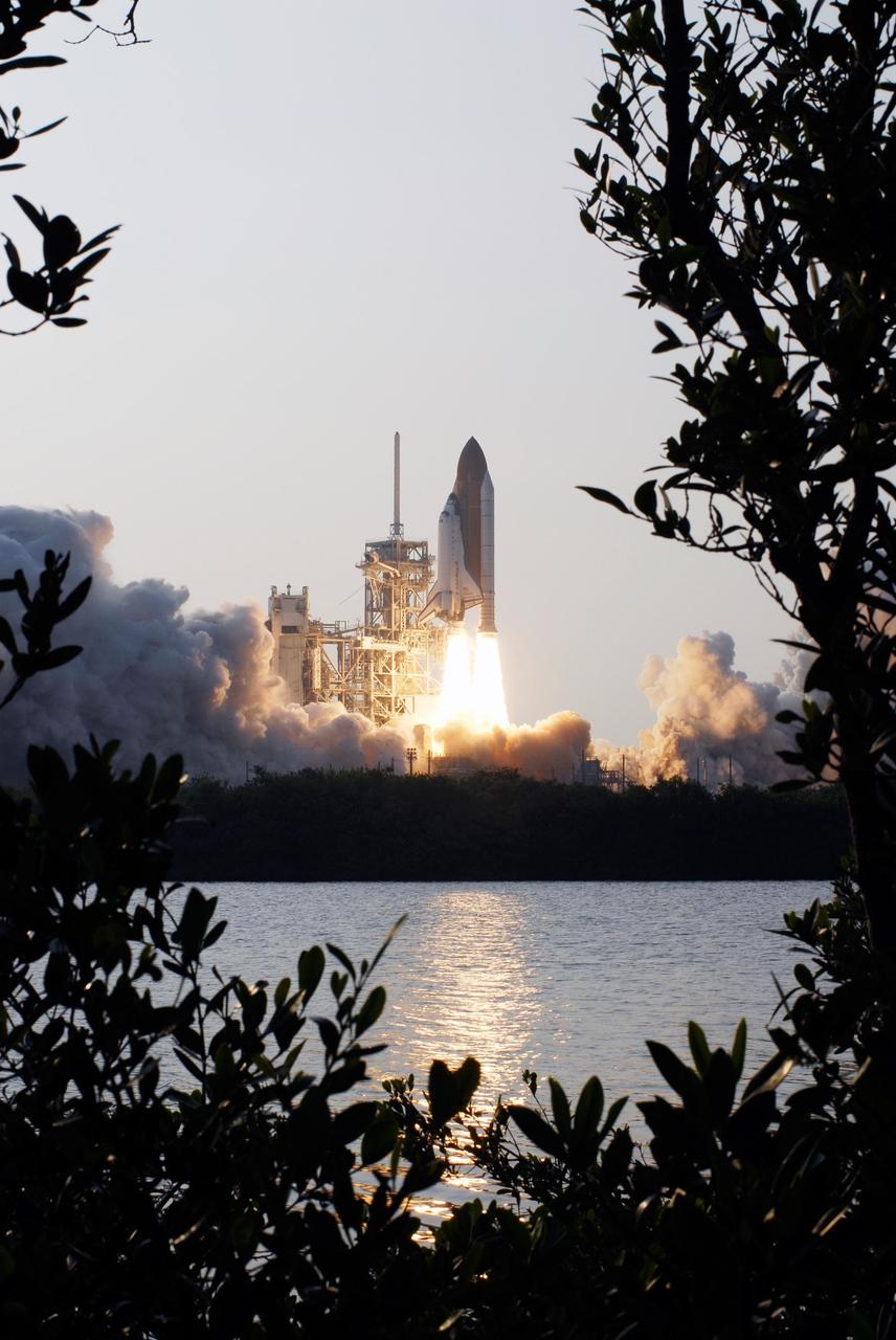 KENNEDY SPACE CENTER, FLA. -- Framed by the trees across the water, Space Shuttle Endeavour roars into the sky as it rises from clouds of smoke and steam billowing across Launch Pad 39A.  Liftoff of Endeavour from Launch Pad 39A on mission STS-118 was on time at 6:36 p.m. EDT.  The mission is the 22nd shuttle flight to the International Space Station. It will continue space station construction by delivering a third starboard truss segment, S5, and other payloads such as the SPACEHAB module and the external stowage platform 3.  The 11-day mission may be extended to as many as 14 depending on the test of the Station-to-Shuttle Power Transfer System that will allow the docked shuttle to draw electrical power from the station and extend its visits to the orbiting lab.  Photo credit: NASA/Sandra Joseph, Tony Gray, Robert Murray