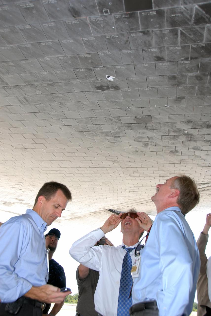 KENNEDY SPACE CENTER, FLA. --  On the Shuttle Landing Facility at NASA's Kennedy Space Center, Mission Launch Integration Director Leroy Cain, NASA Administrator Mike Griffin and Associate Administrator for NASA Space Operations William Gerstenmaier get a closer look at the damaged tiles on the underside of Endeavour.   The damage to the tiles occurred from a piece of foam on the external tank during launch of Space Shuttle Endeavour on mission STS-118 on Aug. 8.  After extensive engineering analysis of such images and testing on the ground, the Mission Management Team decided the tile did not pose a risk to the crew during re-entry.  Endeavour landed safely at 12:32 p.m. EDT at NASA's Kennedy Space Center after a 13-day mission to the International Space Station.  The STS-118 mission installed a new gyroscope, an external spare parts platform and another truss segment to the expanding station.   Photo credit: NASA/Kim Shiflett
