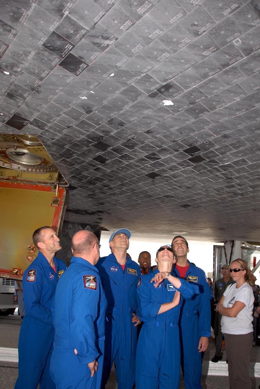 KENNEDY SPACE CENTER, FLA. --  Members of the STS-118 crew take a close look at the damaged tile on the underside of Endeavour.  From left are Pilot Charlie Hobaugh,  Commander Scott Kelly and Mission Specialists Dave Williams, Tracy Caldwell and Rick Mastracchio.  On the mission, the crew installed a new gyroscope, an external spare parts platform and another truss segment to the expanding station.  Endeavour's main gear touched down at 12:32:16  p.m. EDT.  Nose gear touchdown was at 12:32:29 p.m. and wheel stop was at 12:33:20 p.m.  Endeavour landed on orbit 201. STS-118 was the 119th space shuttle flight, the 22nd flight to the station, the 20th flight for Endeavour and the second of four missions planned for 2007. This was the 65th landing of an orbiter at Kennedy.  Photo credit:  NASA/Kim Shiflett
