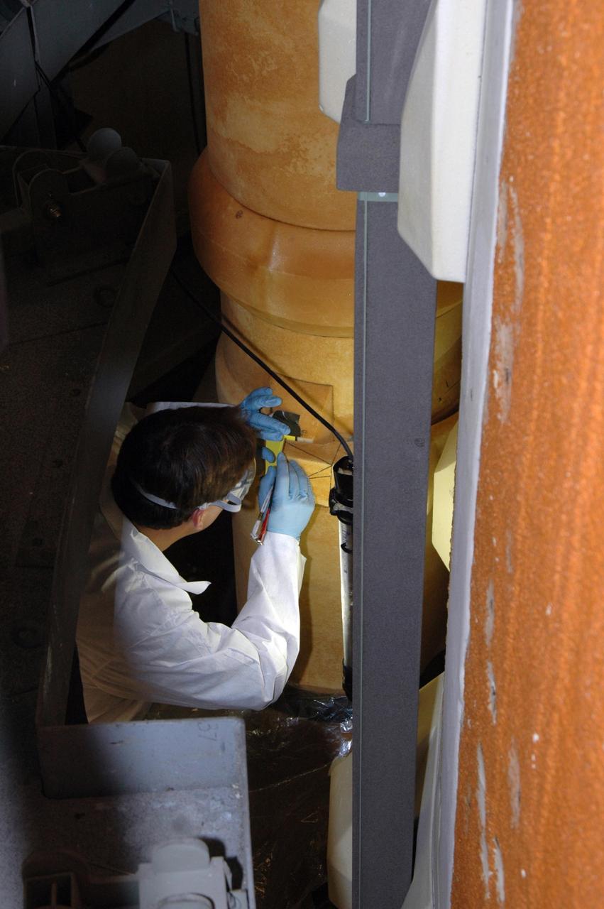 KENNEDY SPACE CENTER, FLA. --  A United Space Alliance external tank technician maps out the cutting area of the liquid oxygen (LO2) feed line bracket where BX265 foam insulation and super lightweight ablator, or SLA, cork insulation is to be removed.  The BX265 foam insulation will later be reapplied without the SLA.  The tank is scheduled to fly on Space Shuttle Discovery in October 2007 on mission STS-120.  Discovery's crew will add the module Harmony that will serve as a port for installing additional international laboratories. Harmony will be the first expansion of the living and working space on the complex since the Russian Pirs airlock was installed in 2001. The mission also will move the first set of solar arrays installed on the station to a permanent location on the complex and redeploy them.  Photo credit: NASA/Jim Grossmann