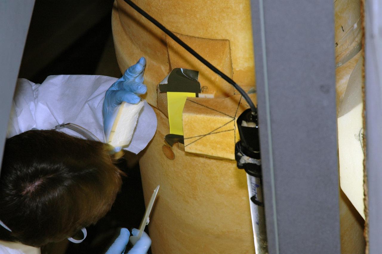 KENNEDY SPACE CENTER, FLA. -- A United Space Alliance external tank technician has completed the removal of a layer of BX265 foam insulation from the LO2 feed line bracket on the external tank. The BX265 foam insulation will later be reapplied without the super lightweight ablator, or SLA, cork insulation.  The tank is scheduled to fly on Space Shuttle Discovery in October 2007 on mission STS-120.  Discovery's crew will add the module Harmony that will serve as a port for installing additional international laboratories. Harmony will be the first expansion of the living and working space on the complex since the Russian Pirs airlock was installed in 2001. The mission also will move the first set of solar arrays installed on the station to a permanent location on the complex and redeploy them.  Photo credit: NASA/Jim Grossmann
