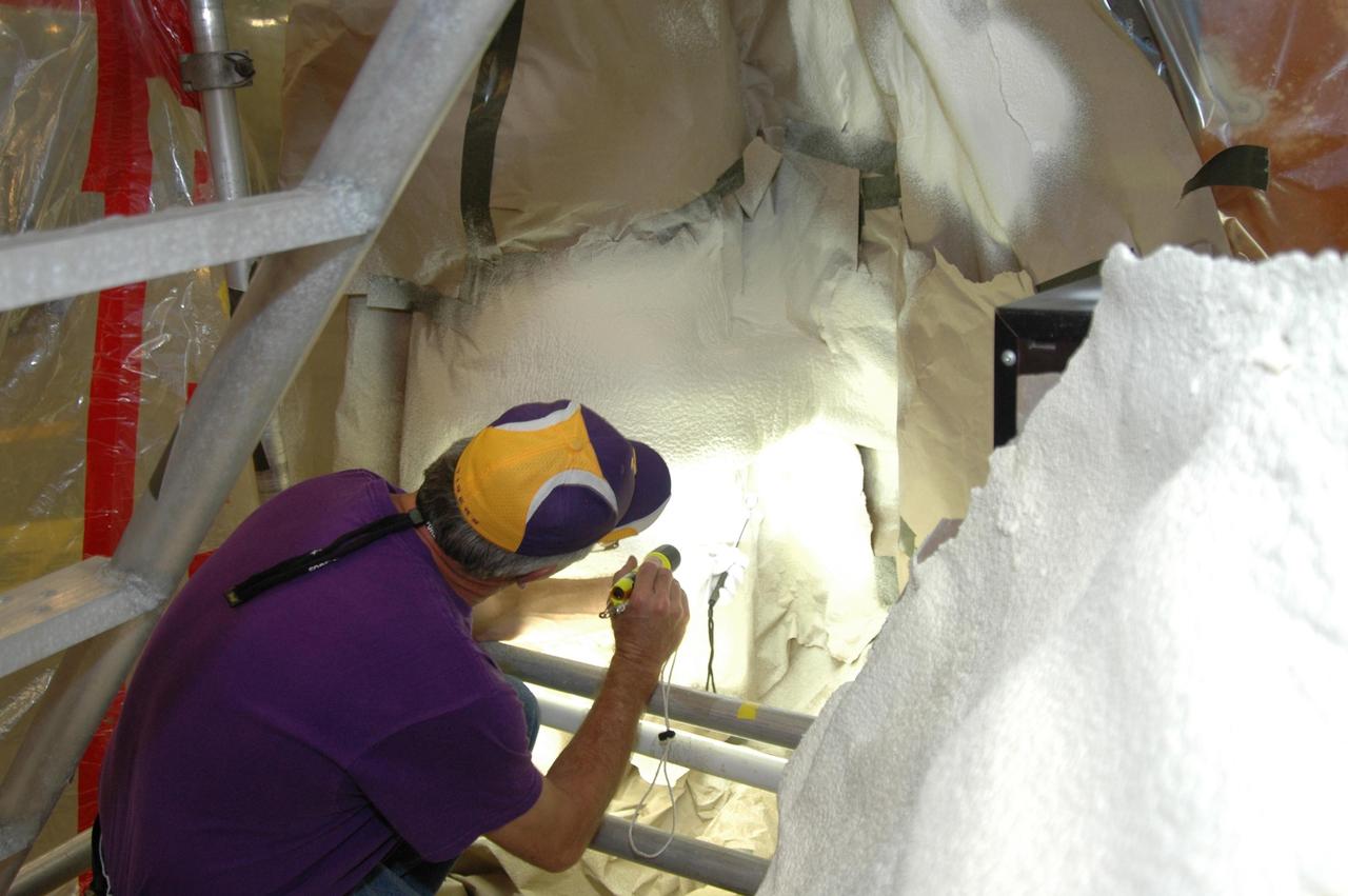 KENNEDY SPACE CENTER, FLA. -- A Lockheed Martin external tank technician from the Michoud Assembly Facility in New Orleans inspects the foam modification on external tank 120 in the Vehicle Assembly Building.  The foam insulation and super lightweight ablator cork insulation were removed from the external tank and LO2 feed line bracket on Aug. 24 and replaced only with BX265 foam insulation.   The tank is scheduled to fly on Space Shuttle Discovery in October 2007 on mission STS-120.  Photo credit: NASA/Jim Grossmann