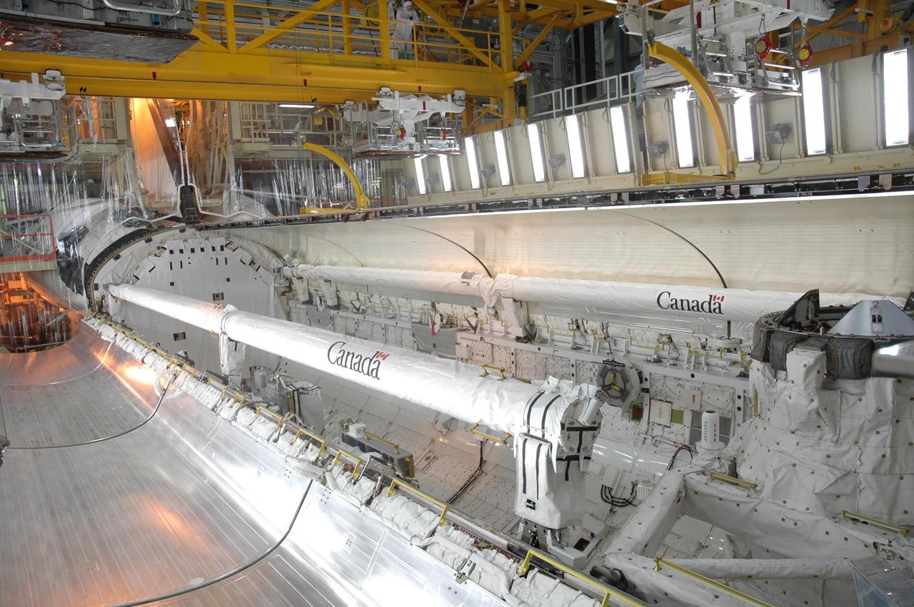 KENNEDY SPACE CENTER, FLA. -- In the Orbiter Processing Facility, the left payload bay door of Discovery is being closed in preparation for the rollover of the orbiter to the Vehicle Assembly Building. Seen along the edges of the bay are the Canadian-built shuttle robotic arm and orbiter boom sensor system. The primary payload, the U.S. Node 2, which is named Harmony, will be installed in the payload bay at the pad prior to Discovery's liftoff on mission STS-120. The mission will be the 23rd flight for the assembly of the International Space Station. Space Shuttle Discovery is targeted for launch on Oct. 23. Photo credit: NASA/Jim Grossmann