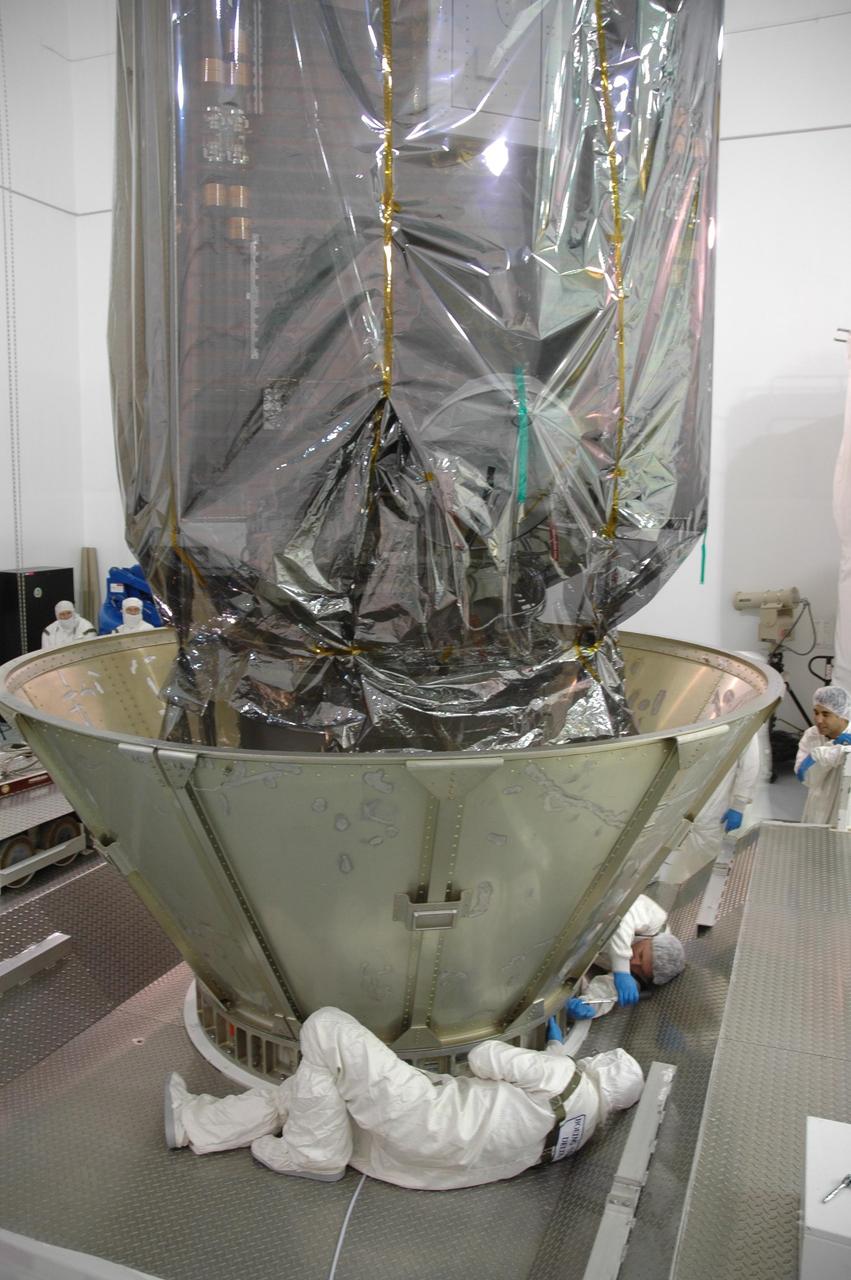 KENNEDY SPACE CENTER, FLA. -- At Astrotech Space Operations in Titusville, Fla., workers check the fitting on the lower transportation canister segments in place around the upper stage booster beneath the Dawn spacecraft.  The canister will protect the spacecraft and booster during transfer to Launch Pad 17-B at Cape Canaveral Air Force Station (CCAFS).  During its nearly decade-long mission, the Dawn mission will study the asteroid Vesta and dwarf planet Ceres, celestial bodies believed to have accreted early in the history of the solar system. To carry out its scientific mission, the Dawn spacecraft will carry a visible camera, a visible and infrared mapping spectrometer, and a gamma ray and neutron spectrometer, whose data will be used in combination to characterize these bodies.  In addition to the three instruments, radiometric and optical navigation data will provide data relating to the gravity field and thus bulk properties and internal structure of the two bodies. Data returned from the Dawn spacecraft could provide opportunities for significant breakthroughs in our knowledge of how the solar system formed. Launch via a Delta II rocket is scheduled in a window from 7:25 to 7:54 a.m. Sept. 26 from CCAFS.  Photo credit: NASA/Jim Grossmann