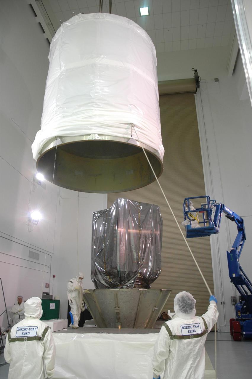 KENNEDY SPACE CENTER, FLA. -- At Astrotech Space Operations in Titusville, Fla., workers guide the upper transportation canister toward the Dawn spacecraft in the background.  The canister will be lowered onto the lower segments and attached.  The canister will protect the spacecraft and booster during transfer to Launch Pad 17-B at Cape Canaveral Air Force Station (CCAFS).  During its nearly decade-long mission, the Dawn mission will study the asteroid Vesta and dwarf planet Ceres, celestial bodies believed to have accreted early in the history of the solar system. To carry out its scientific mission, the Dawn spacecraft will carry a visible camera, a visible and infrared mapping spectrometer, and a gamma ray and neutron spectrometer, whose data will be used in combination to characterize these bodies.  In addition to the three instruments, radiometric and optical navigation data will provide data relating to the gravity field and thus bulk properties and internal structure of the two bodies. Data returned from the Dawn spacecraft could provide opportunities for significant breakthroughs in our knowledge of how the solar system formed. Launch via a Delta II rocket is scheduled in a window from 7:25 to 7:54 a.m. Sept. 26 from CCAFS.  Photo credit: NASA/Jim Grossmann