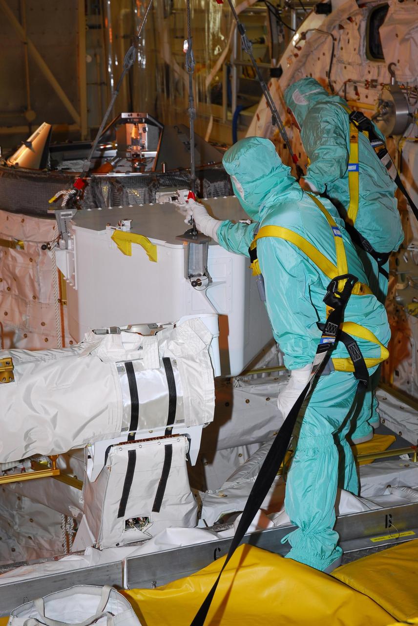 KENNEDY SPACE CENTER, FLA. --  In bay 3 of the Orbiter Processing Facility, workers maneuver the tool storage assembly unit into place in Discovery's payload bay, where it will be stored.  The tools may be used on a spacewalk, yet to be determined, during mission STS-120.    In an unusual operation, the payload bay doors had to be reopened after closure to accommodate the storage.  Space shuttle Discovery is targeted to launch Oct. 23 to the International Space Station.  It will carry the U.S. Node 2, a connecting module, named Harmony, for assembly on the space station.  Photo credit: NASA/Amanda Diller
