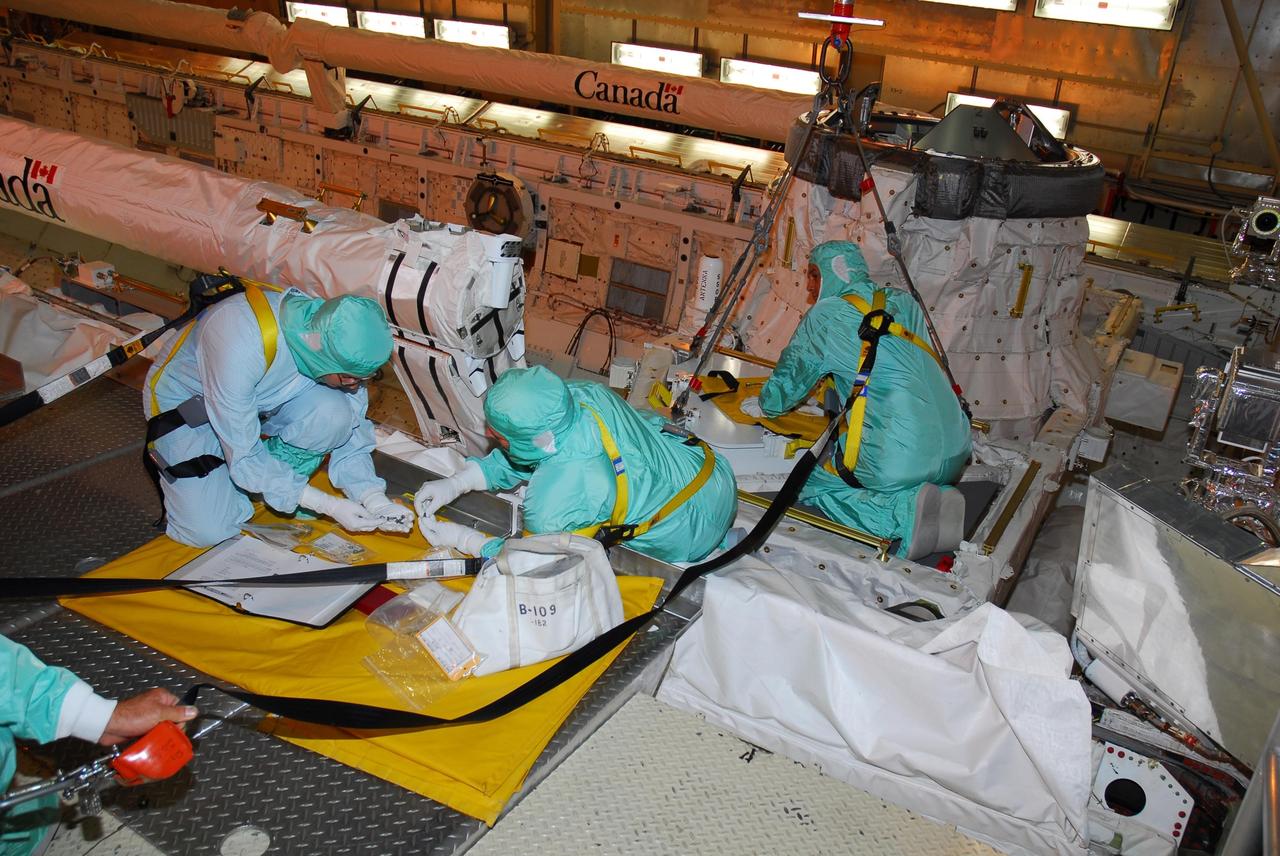 KENNEDY SPACE CENTER, FLA. --  In bay 3 of the Orbiter Processing Facility, workers secure the tool storage assembly unit into place in Discovery's payload bay, where it will be stored. The tools may be used on a spacewalk, yet to be determined, during mission STS-120.    In an unusual operation, the payload bay doors had to be reopened after closure to accommodate the storage.  Space shuttle Discovery is targeted to launch Oct. 23 to the International Space Station.  It will carry the U.S. Node 2, a connecting module, named Harmony, for assembly on the space station.  Photo credit: NASA/Amanda Diller