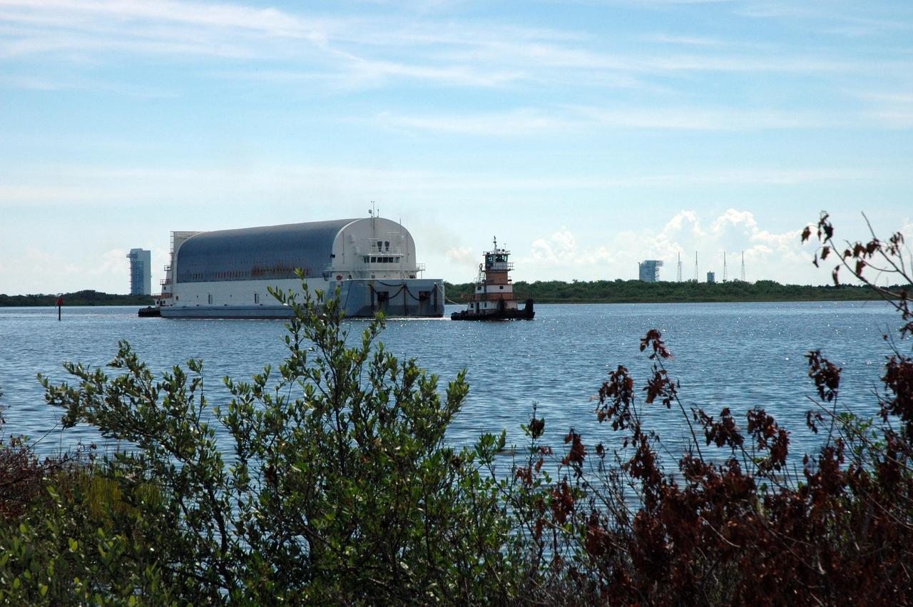 KENNEDY SPACE CENTER, FLA. -- Tugboats tow the Pegasus barge, with its cargo of external tank No. 125, on the Banana River. Seen in the background are the Atlas V (left) and Titan IV launch complexes. After it is offloaded, the tank will be moved to the Vehicle Assembly Building. The external tank will be used on space shuttle Atlantis for mission STS-122 targeted for launch on Dec. 6. Photo credit: NASA/Troy Cryder